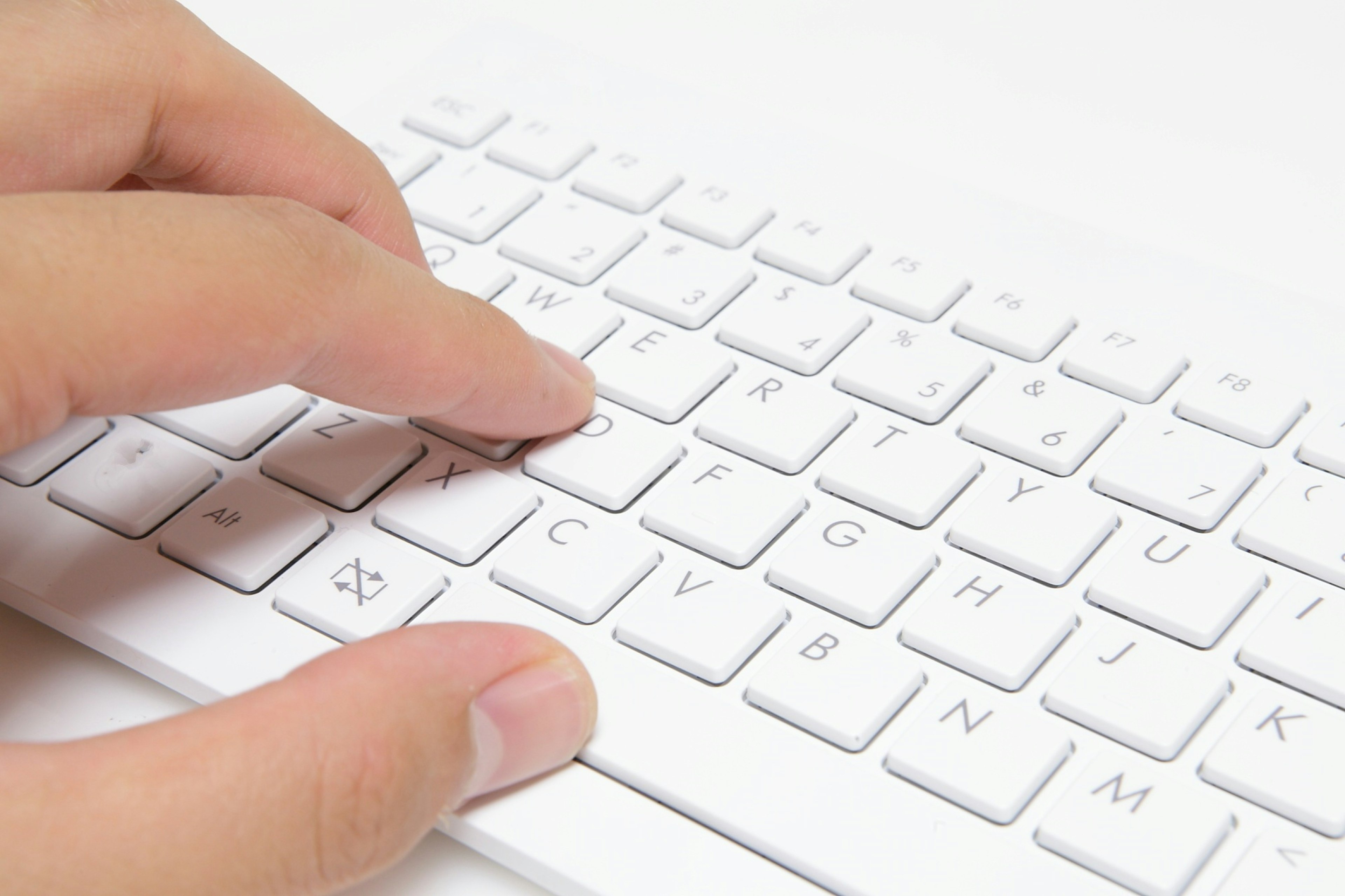 Primer plano de dedos sobre un teclado blanco