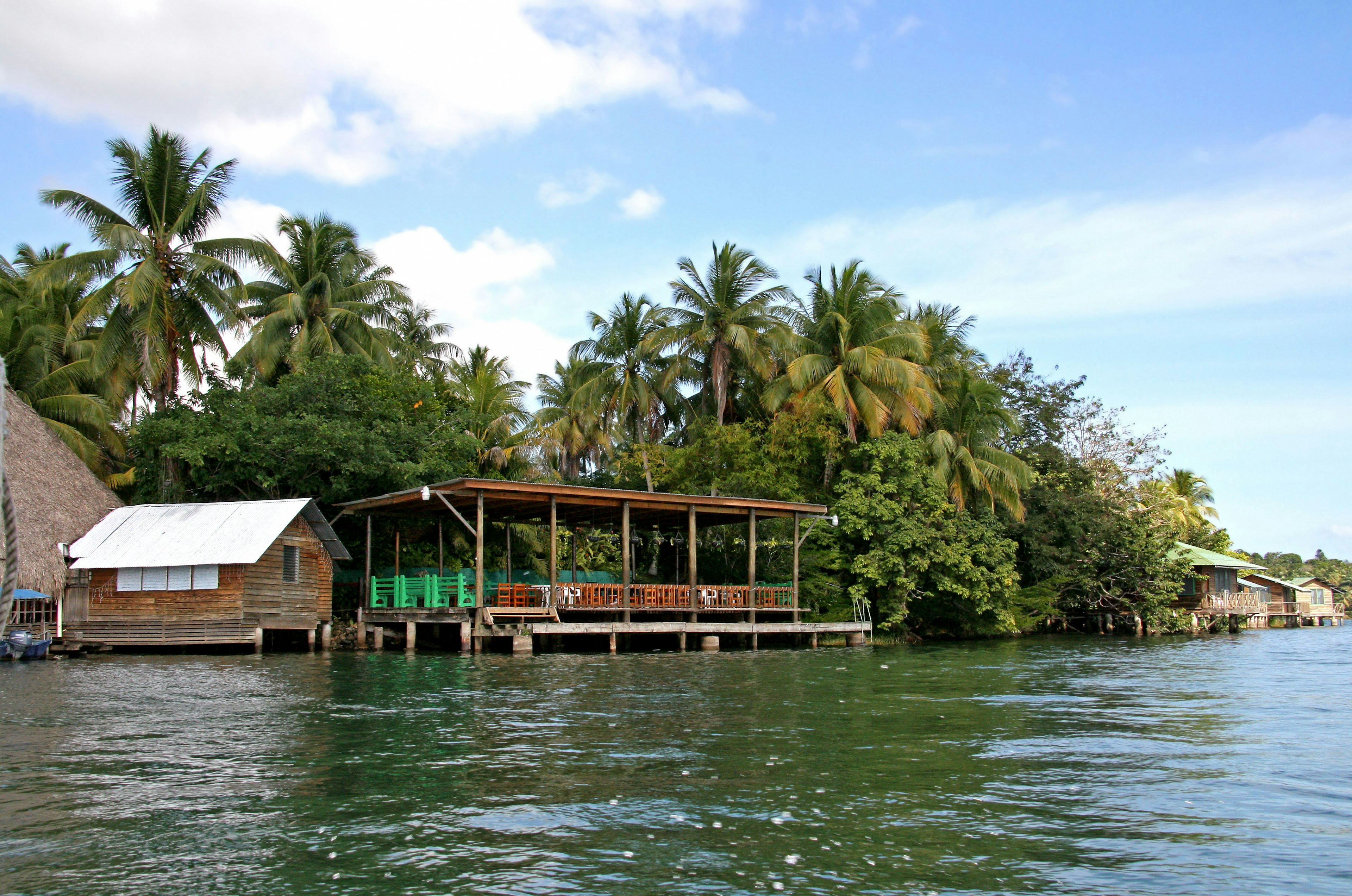 Scenic view of wooden huts by the water surrounded by lush greenery