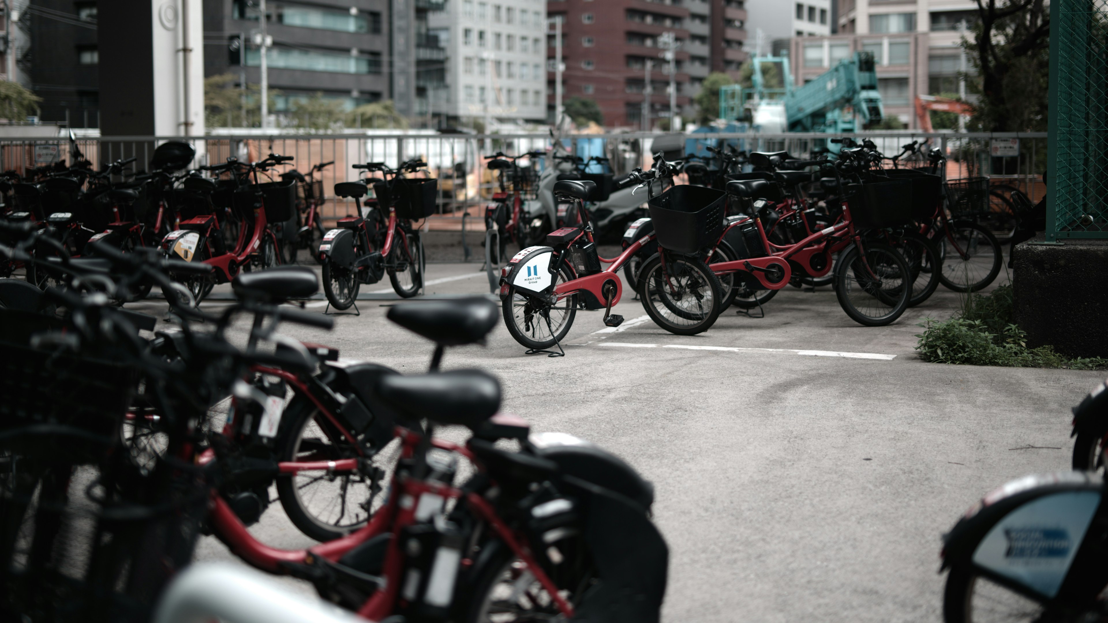 自行車停放區滿是自行車，紅色自行車在城市背景中顯眼