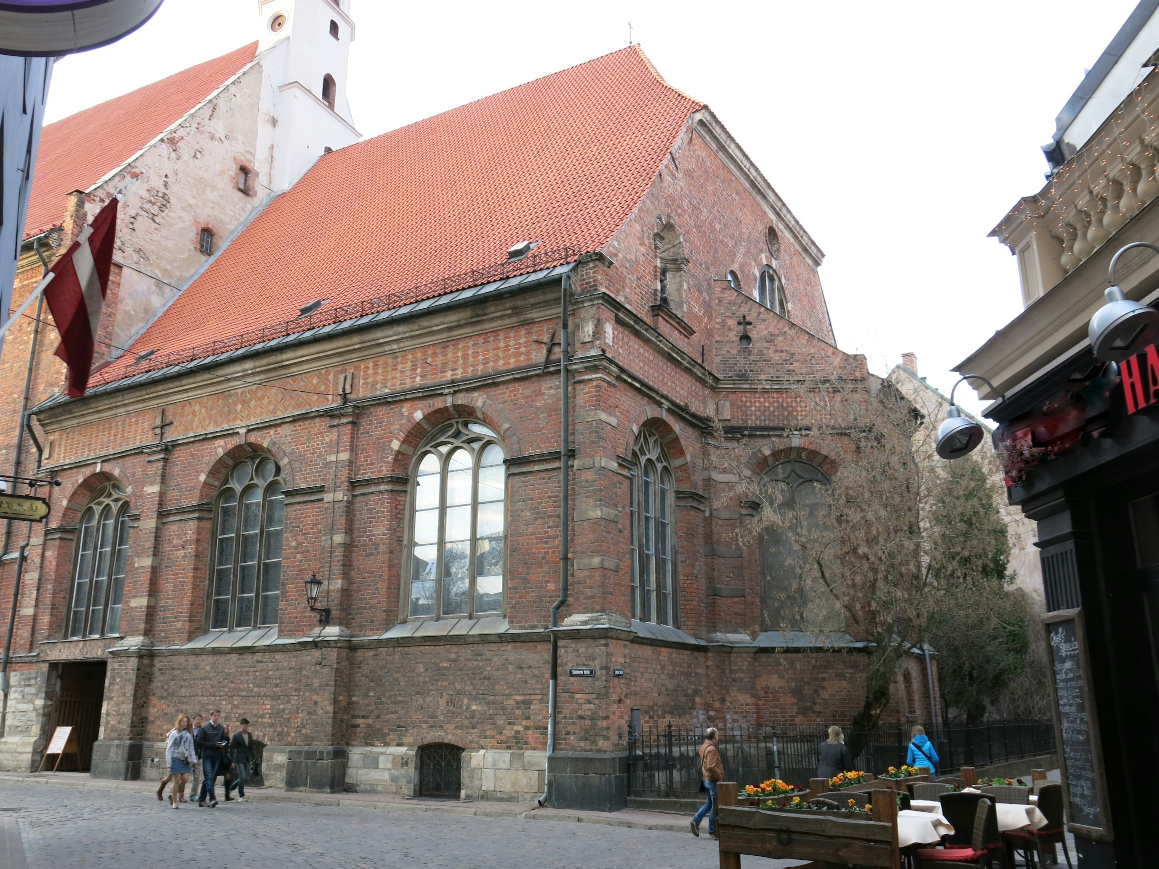 Historic brick church with a red roof people walking nearby