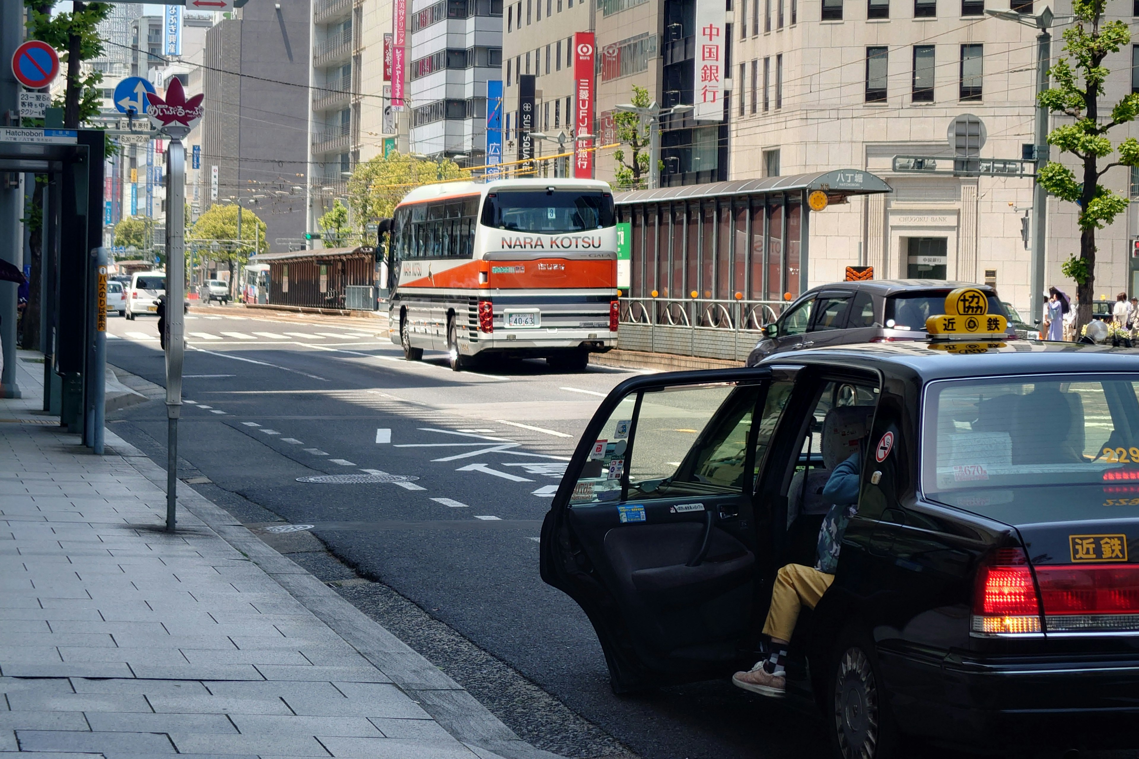 A city street scene featuring a parked taxi and a bus