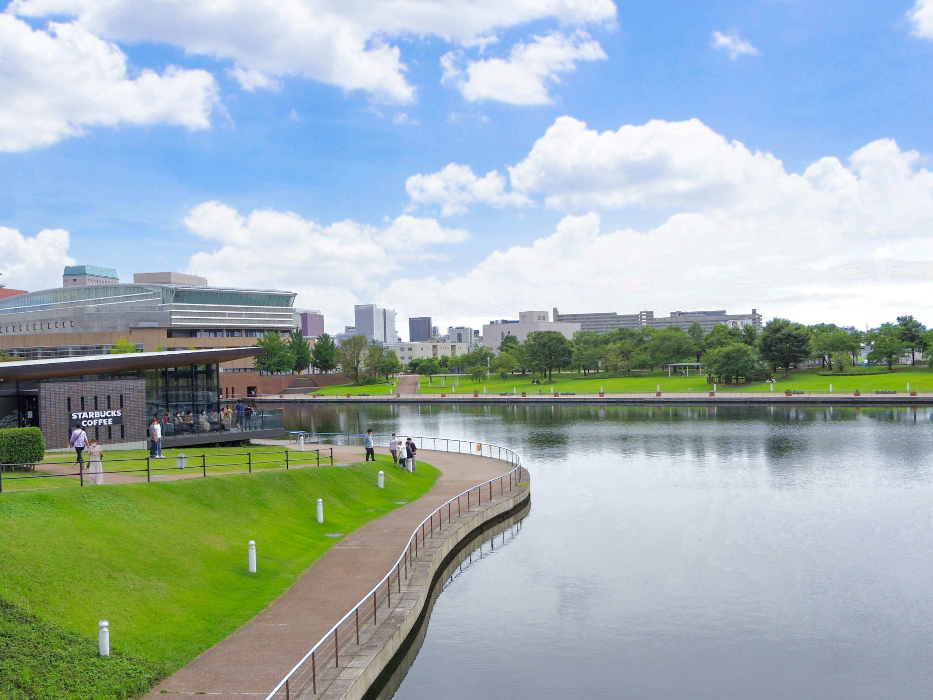 青空の下の公園と川の風景建物と緑の芝生が見える