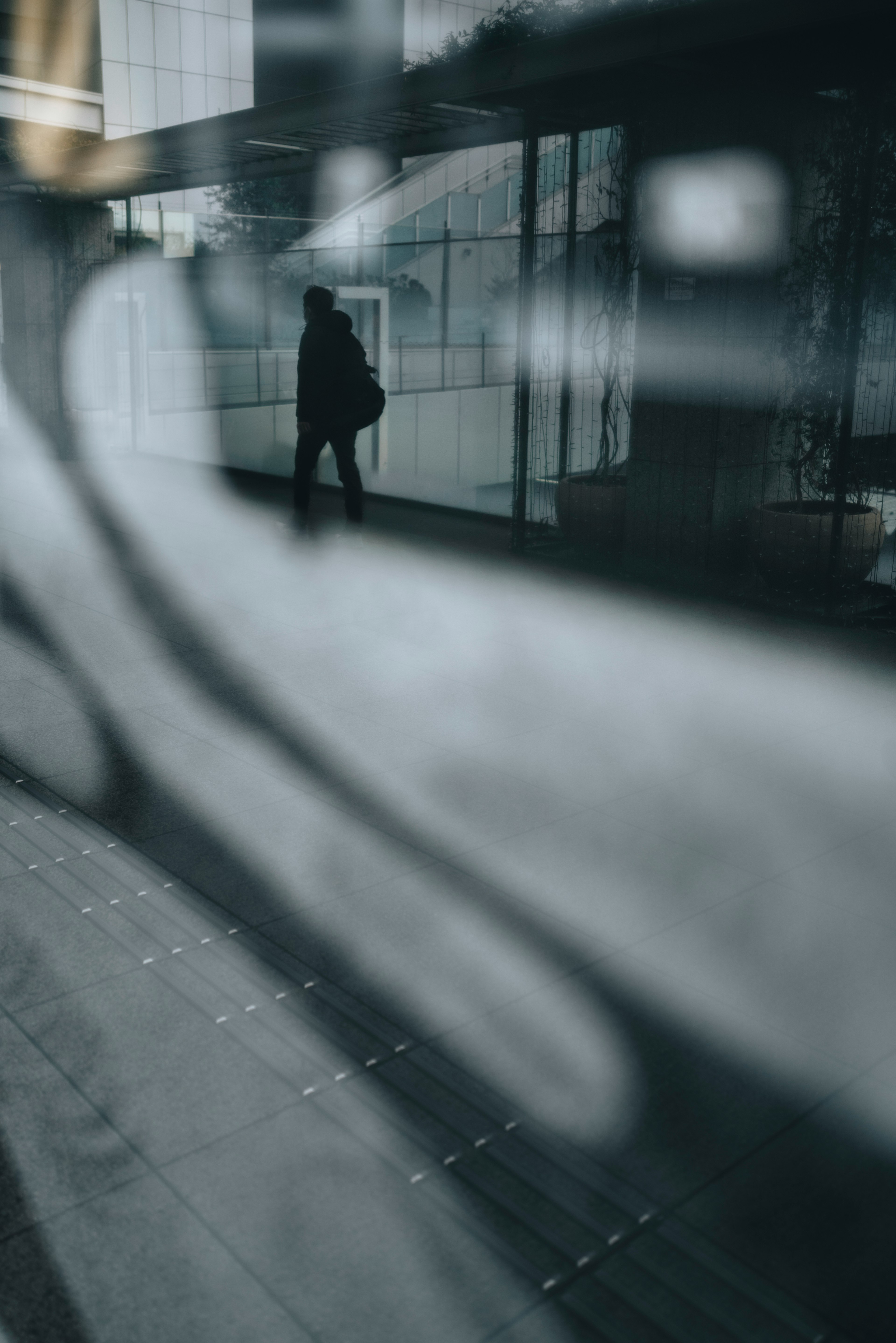 Silhouette of a person walking through glass blurred background modern building