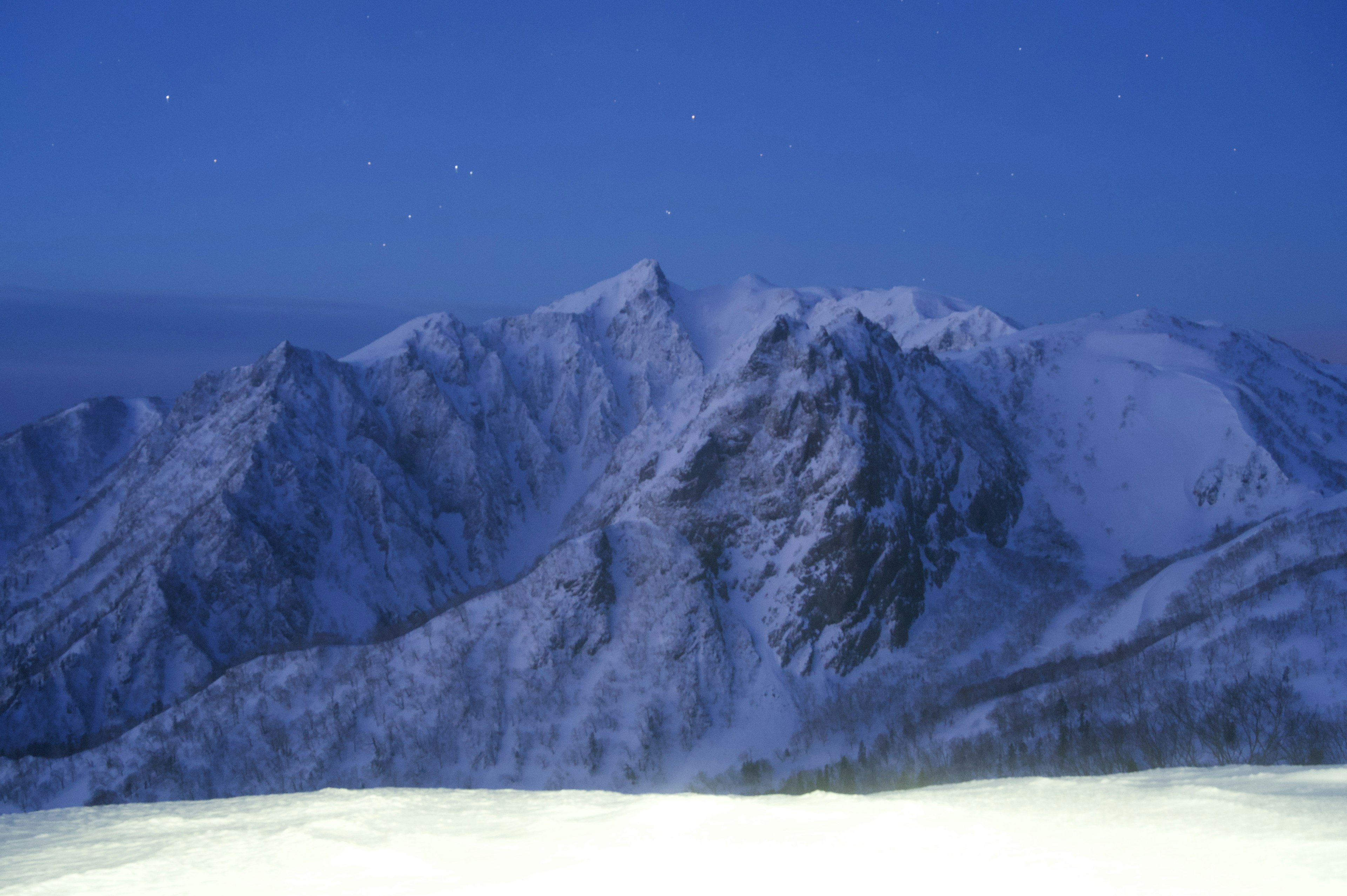 雪に覆われた山々が青い夜空の下に広がる風景