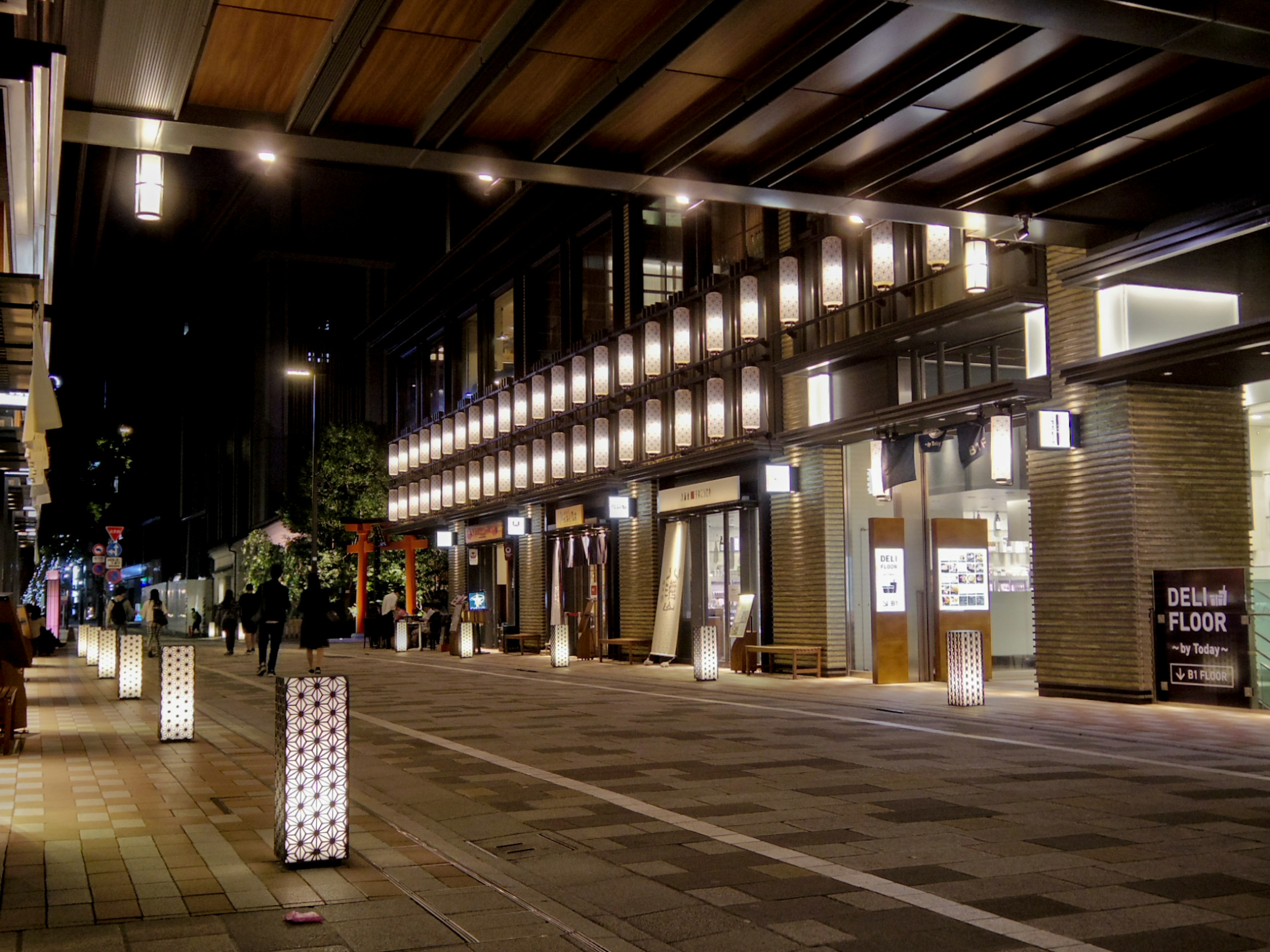 Night scene featuring illuminated storefronts and street lights