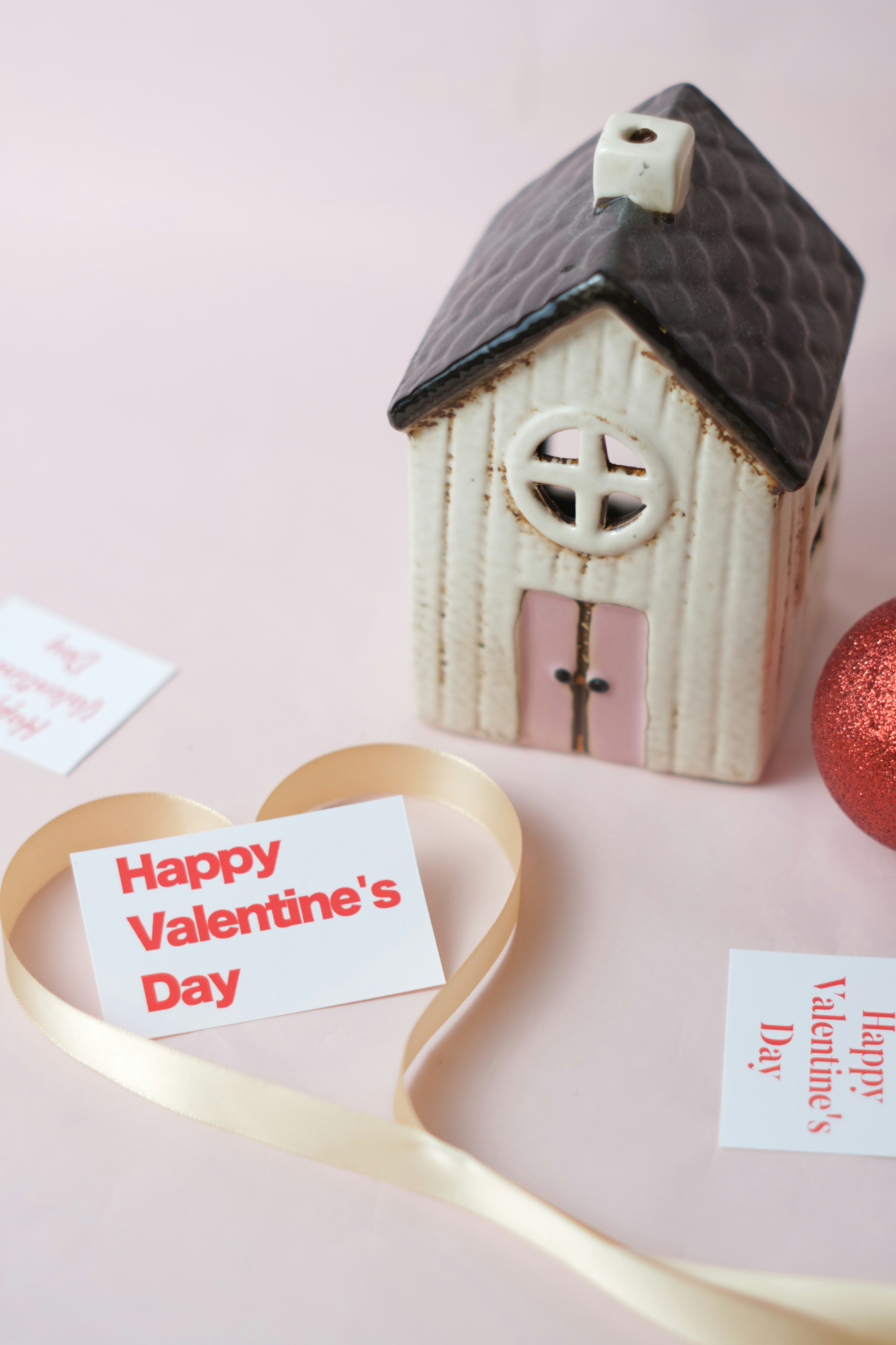 A decorative house with a Valentine's Day message card and ribbon in a heart shape