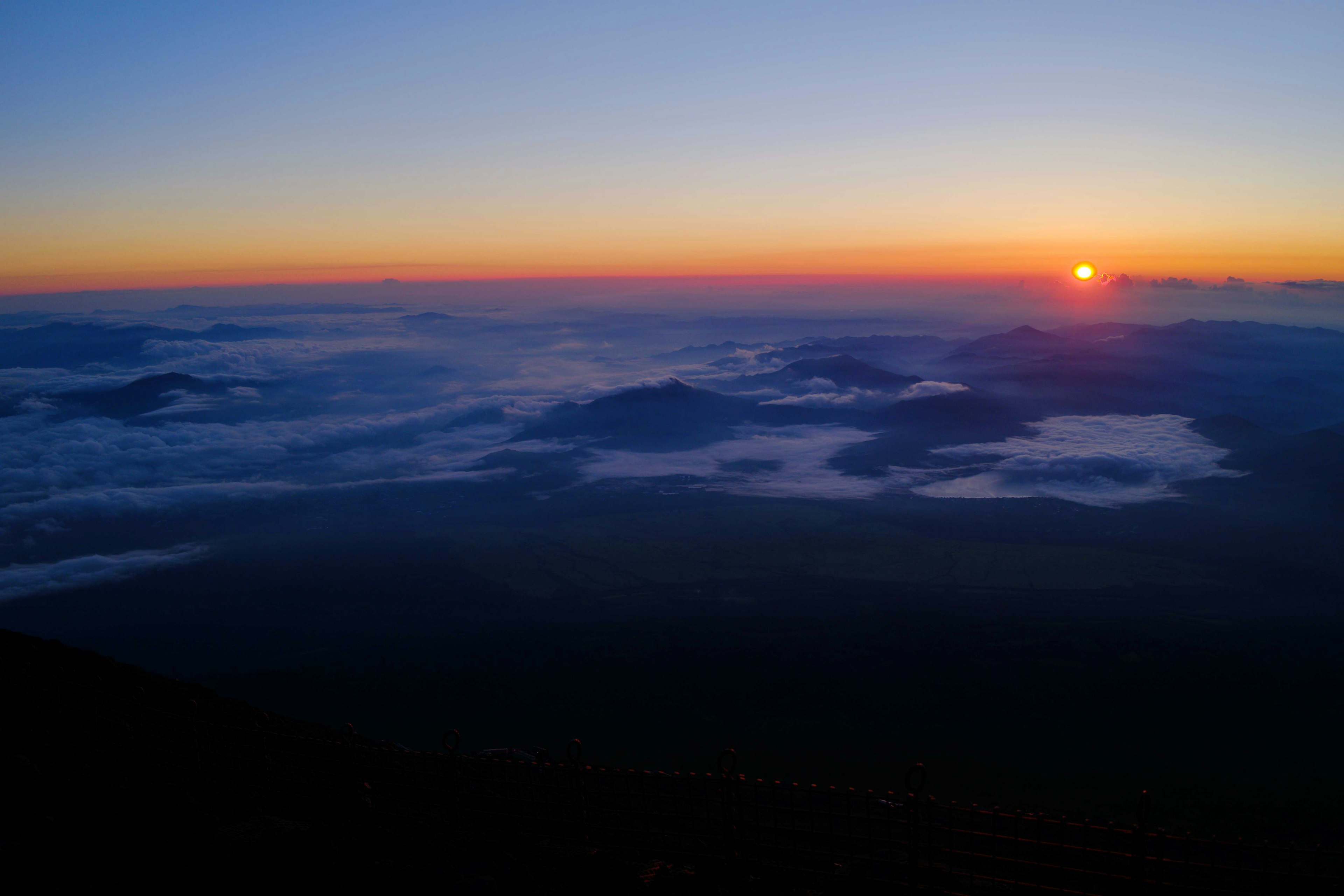 美しい日の出の風景、雲の上に広がる山々、青からオレンジへのグラデーション