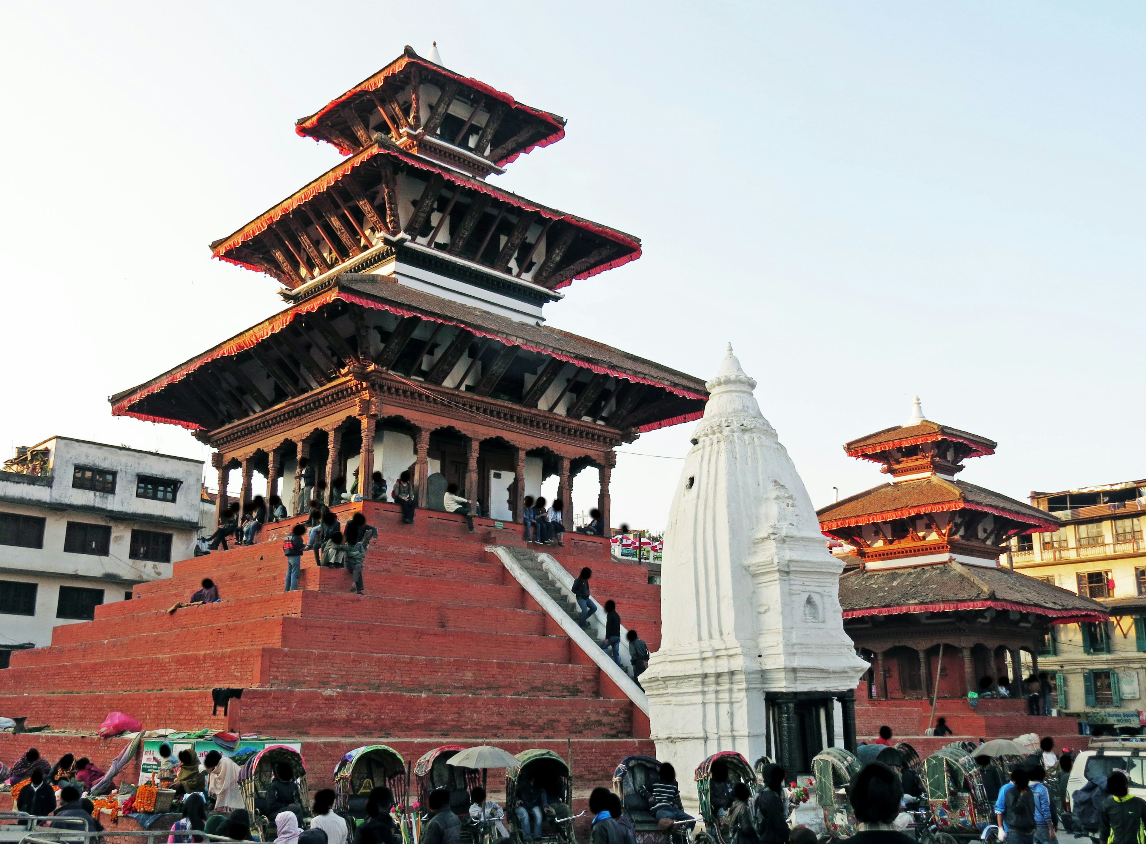 Traditioneller Tempel und Platz in Nepal mit roter Backsteinarchitektur und versammelten Menschen