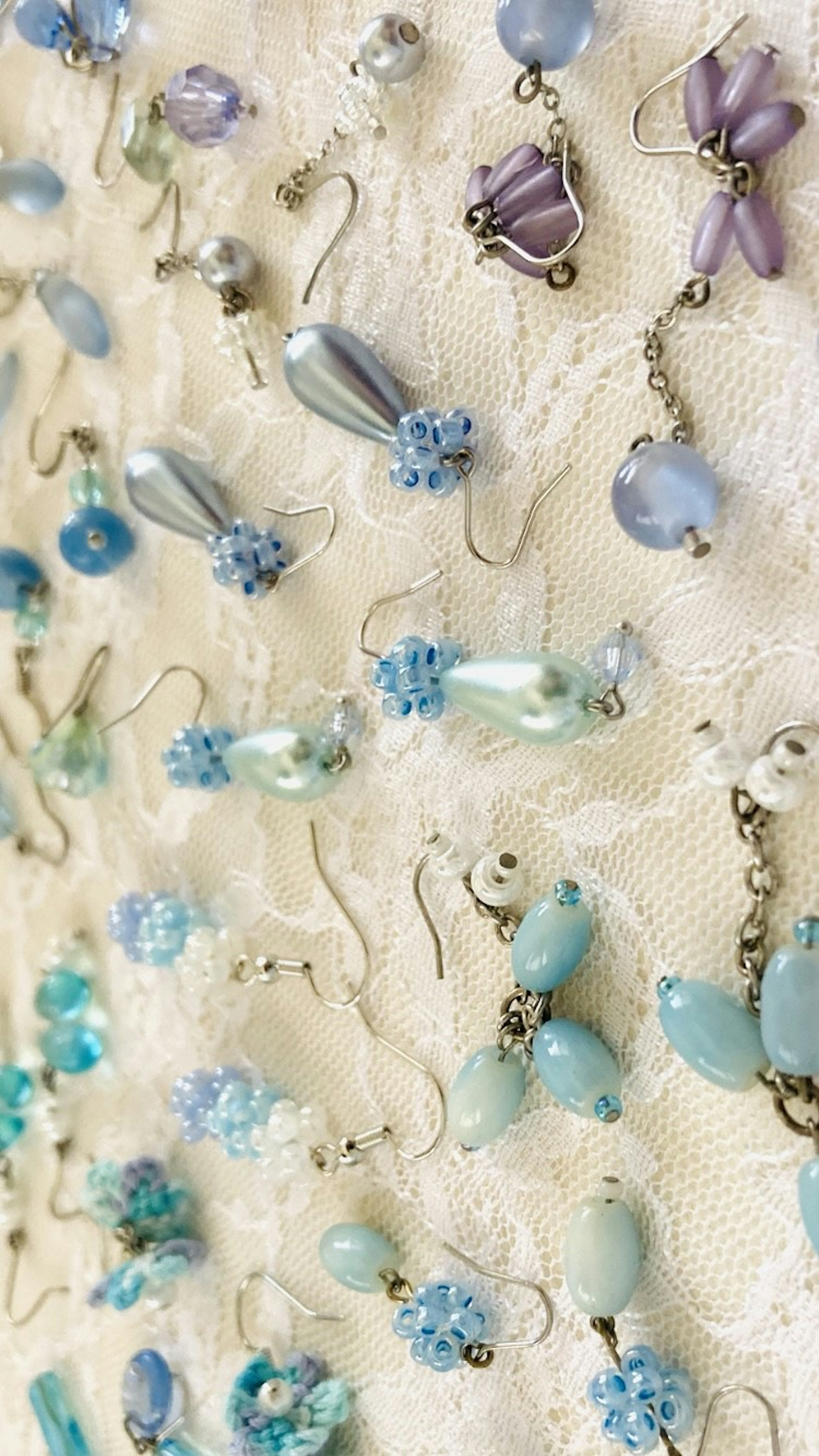 Colorful assortment of beaded and pearl earrings displayed on a lace background