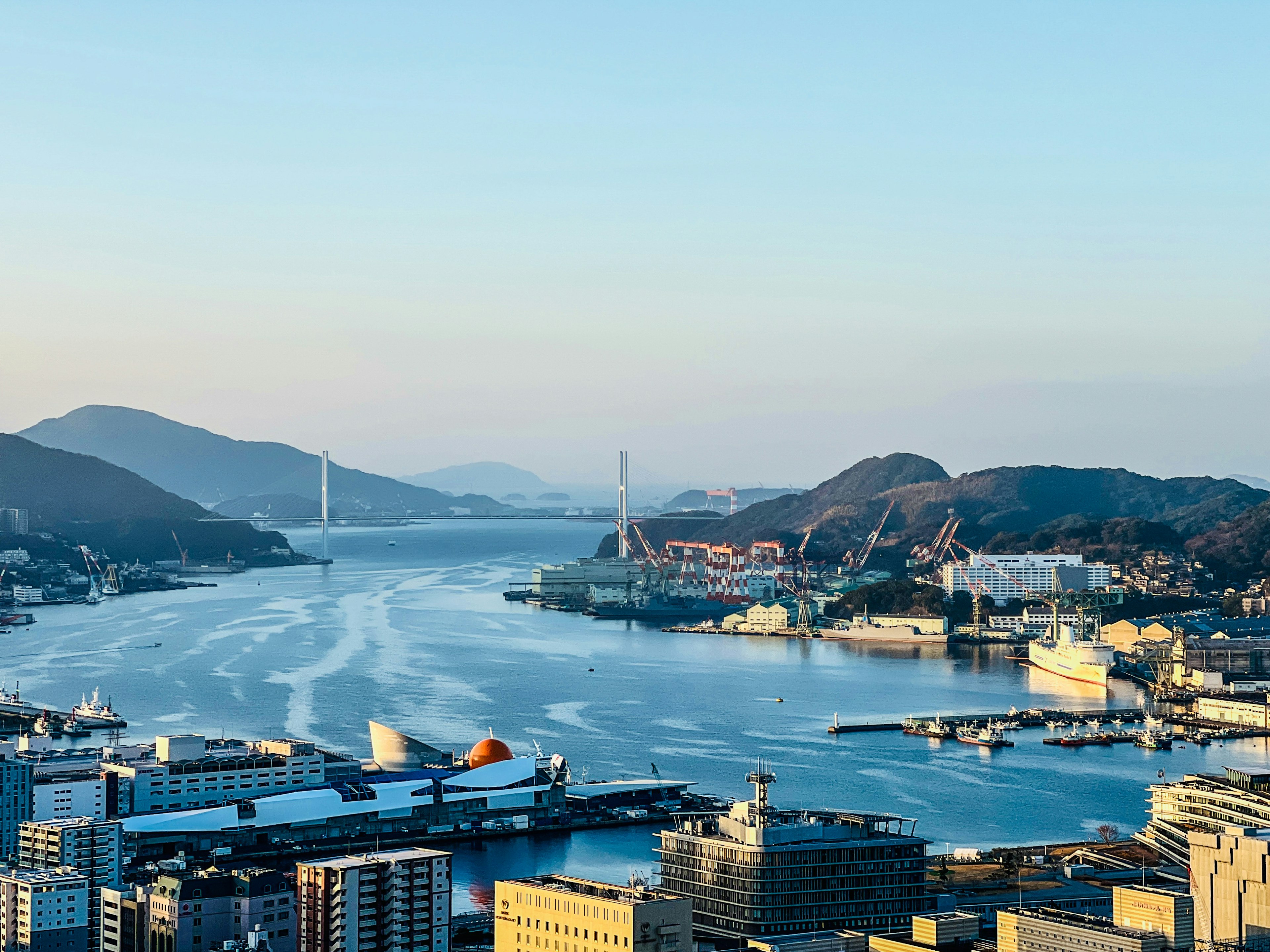 Panoramablick auf einen Hafen und Berge mit einer Brücke