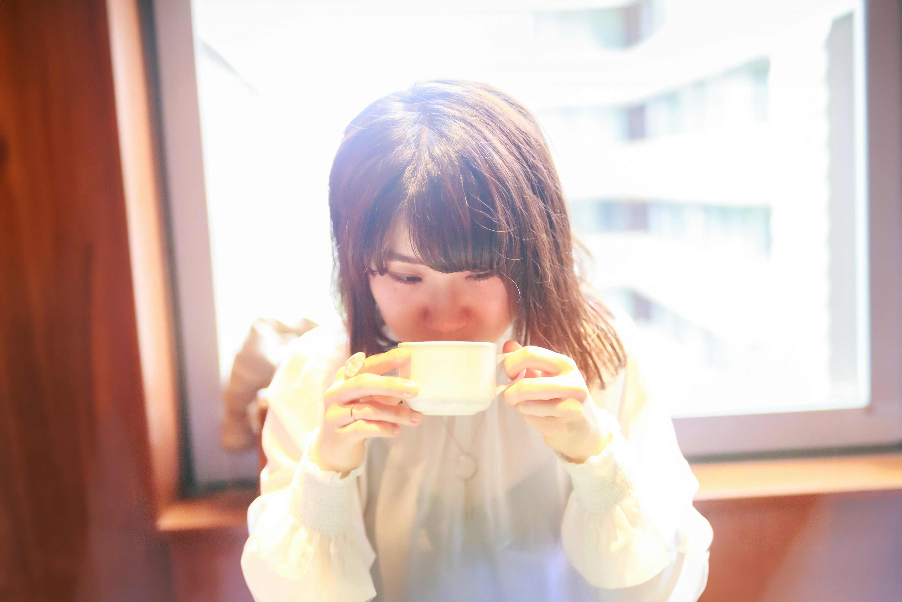 Joven mujer sosteniendo una taza junto a la ventana