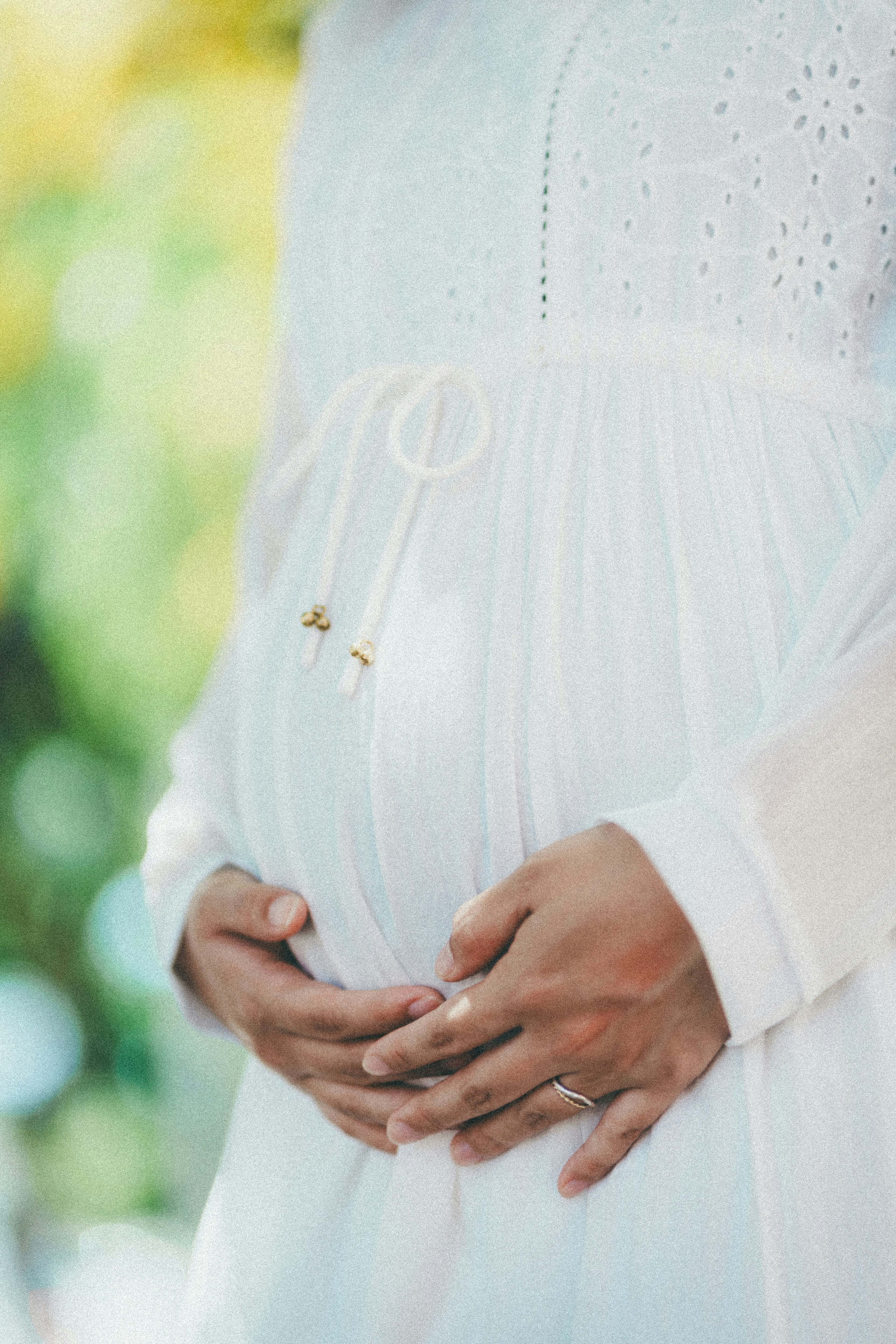 Nahaufnahme einer schwangeren Frau in einem weißen Kleid, die ihren Bauch hält