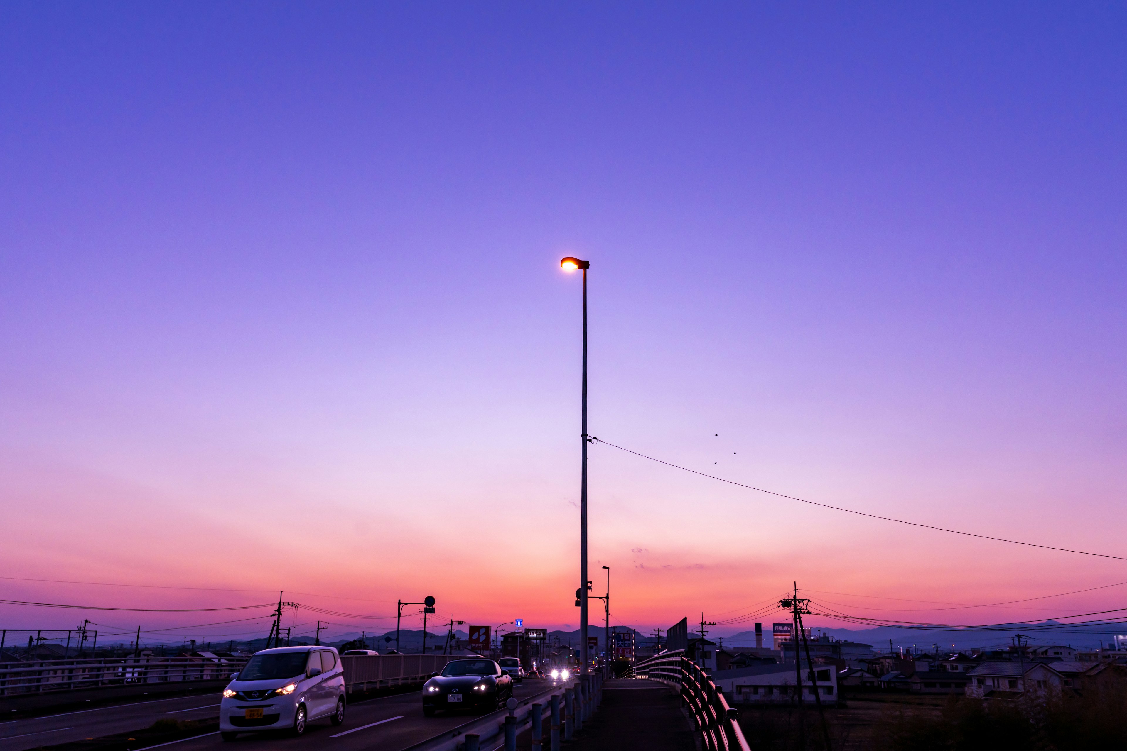 夕焼けの景色に照らされた道路と車両のシルエット