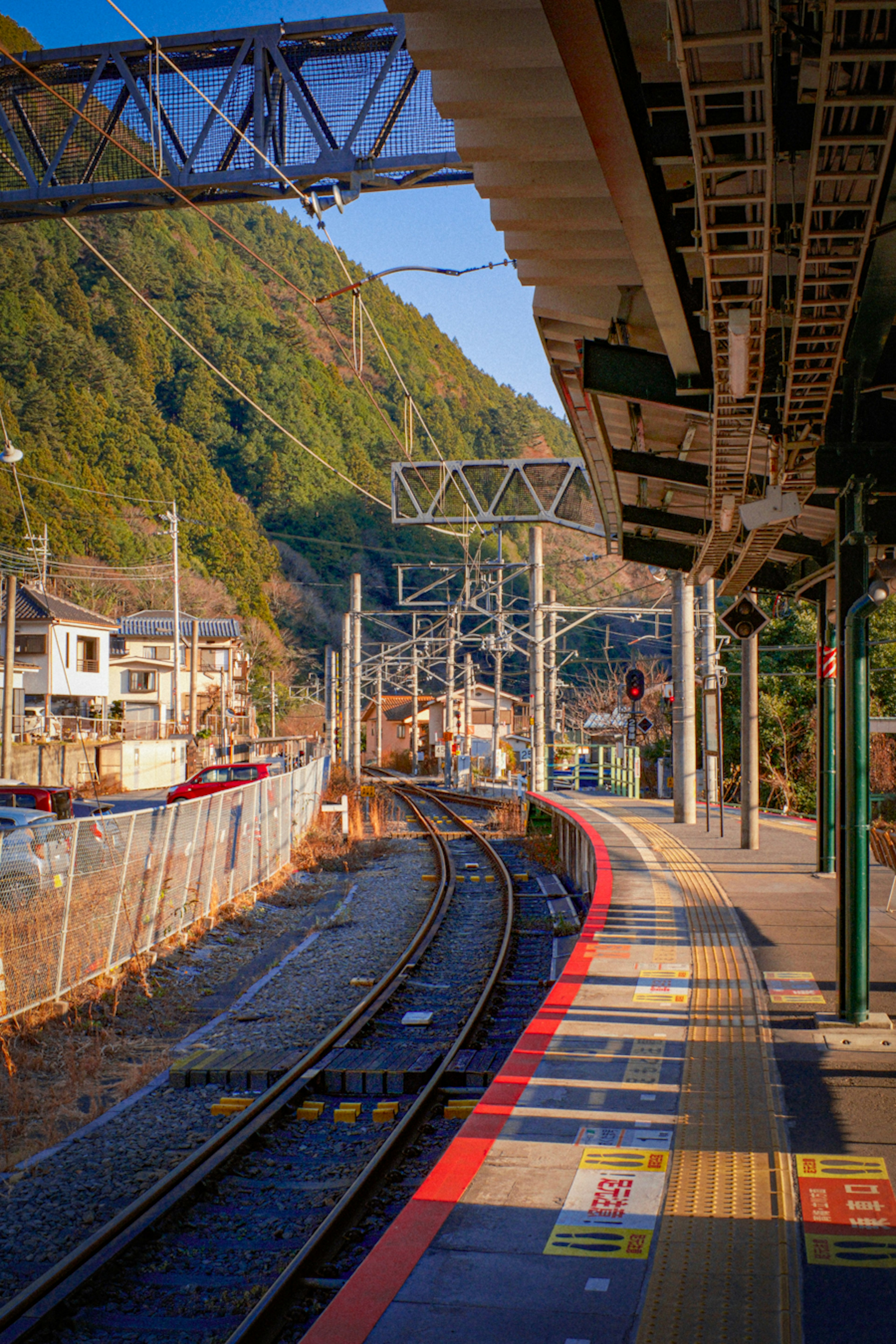 山に囲まれた鉄道駅のプラットフォームと曲がる線路の風景