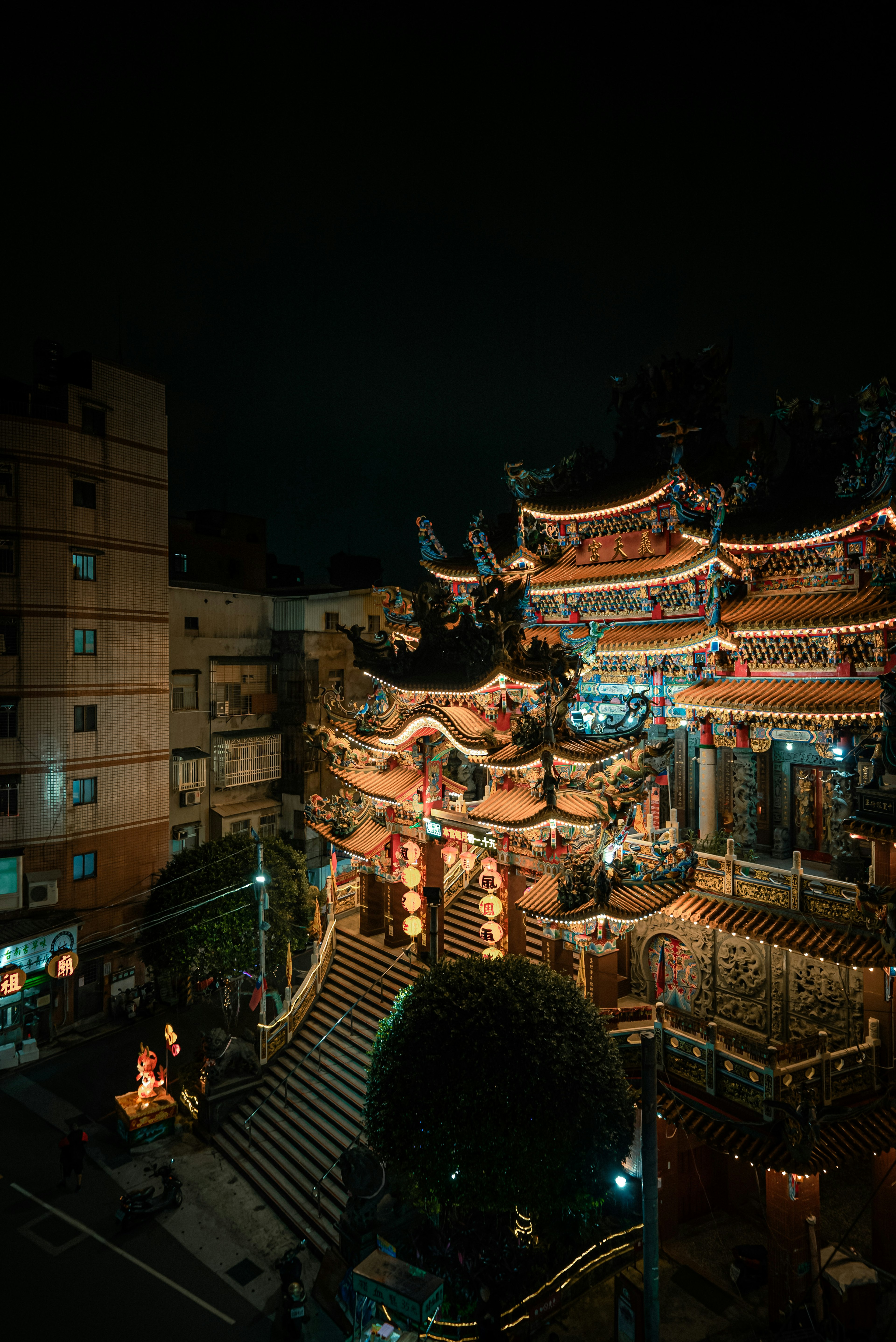 Illuminated temple exterior at night with surrounding buildings