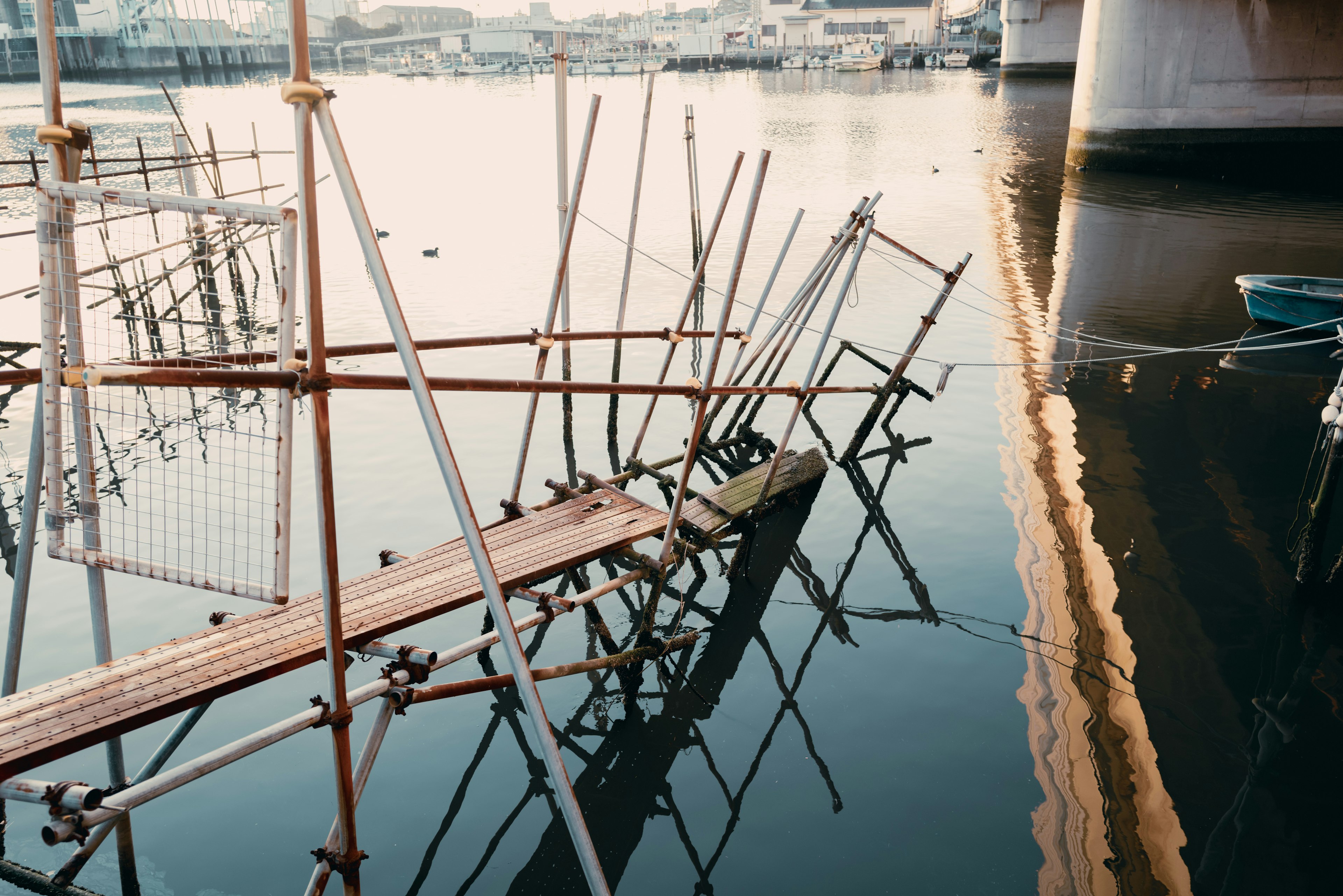 Molo rotto riflesso nell'acqua con impalcature metalliche