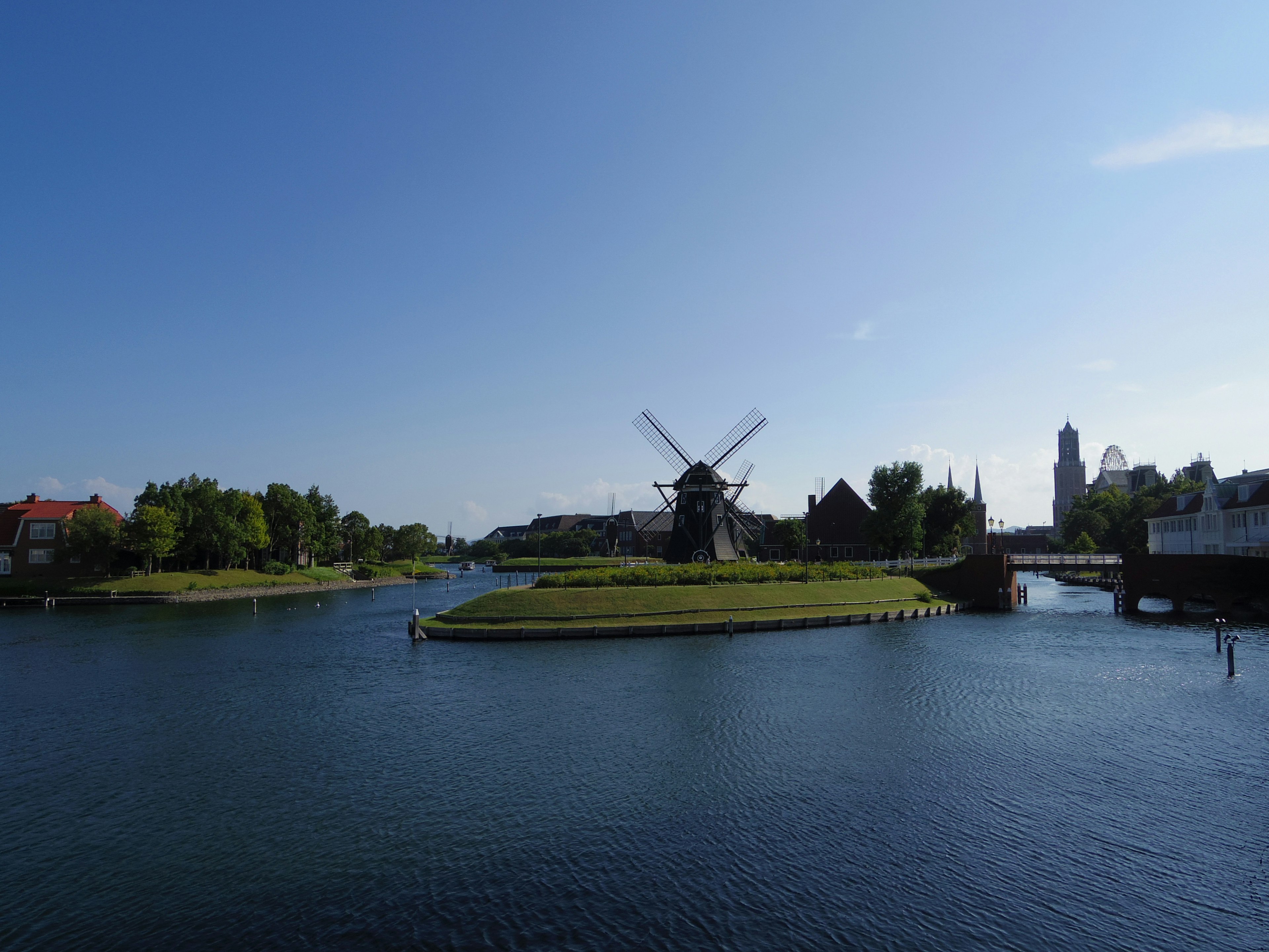 Malersicher Blick auf eine Windmühle und eine grüne Insel entlang eines ruhigen Wasserwegs