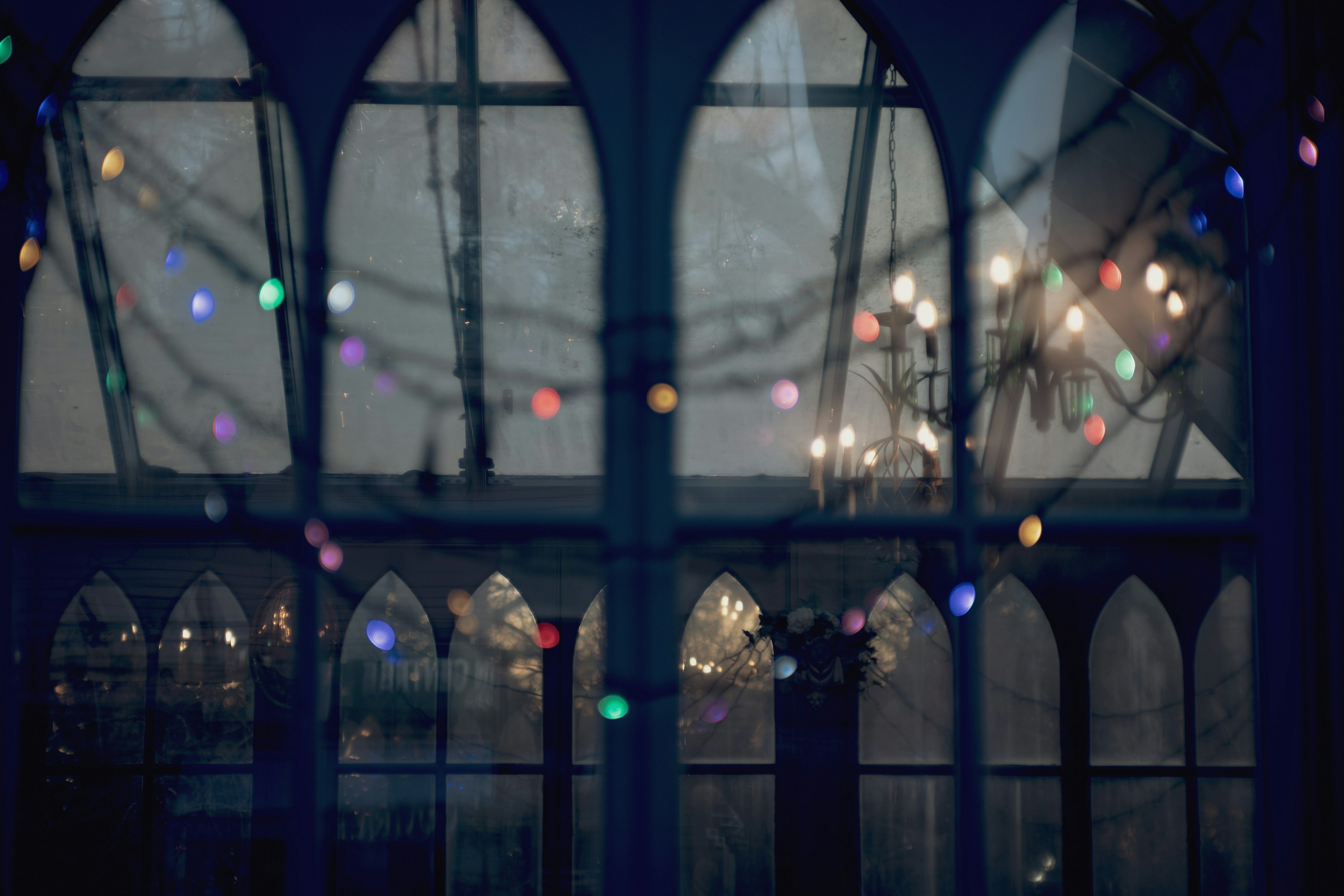 Luces coloridas y brillo de candelabro visibles a través de ventanas interiores oscuras