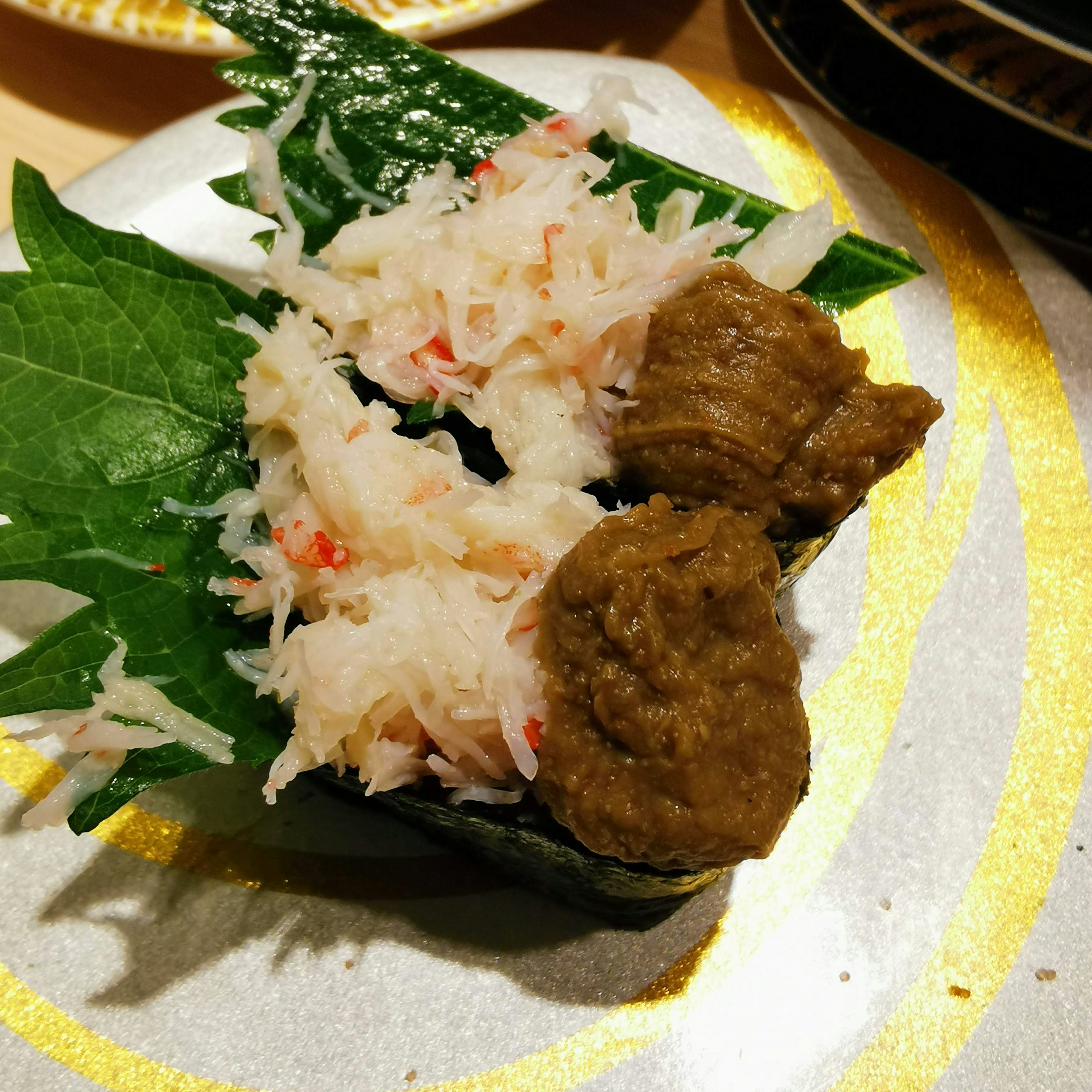 美味的壽司菜餚，上面放有蟹肉和牛肉，配在葉子上