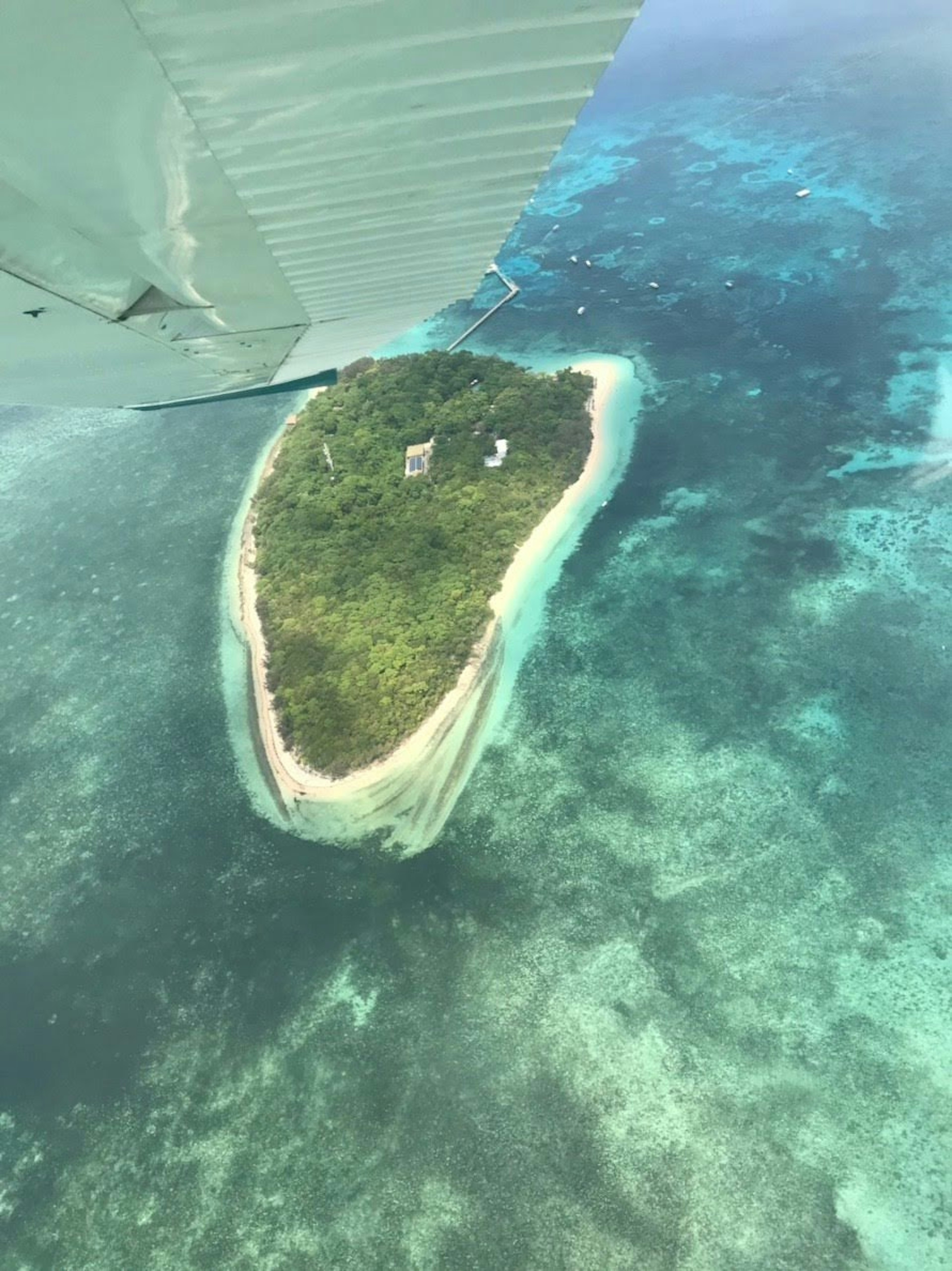 Vue aérienne d'une petite île entourée d'eau bleue avec une végétation luxuriante et une plage de sable