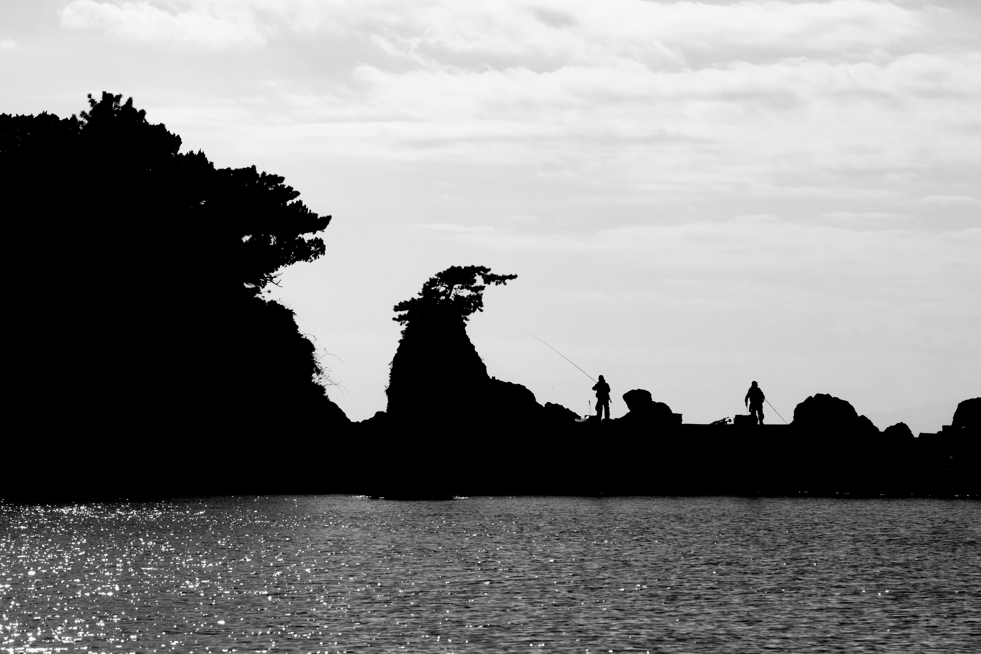 海のシルエットと人物の影が映る白黒の風景