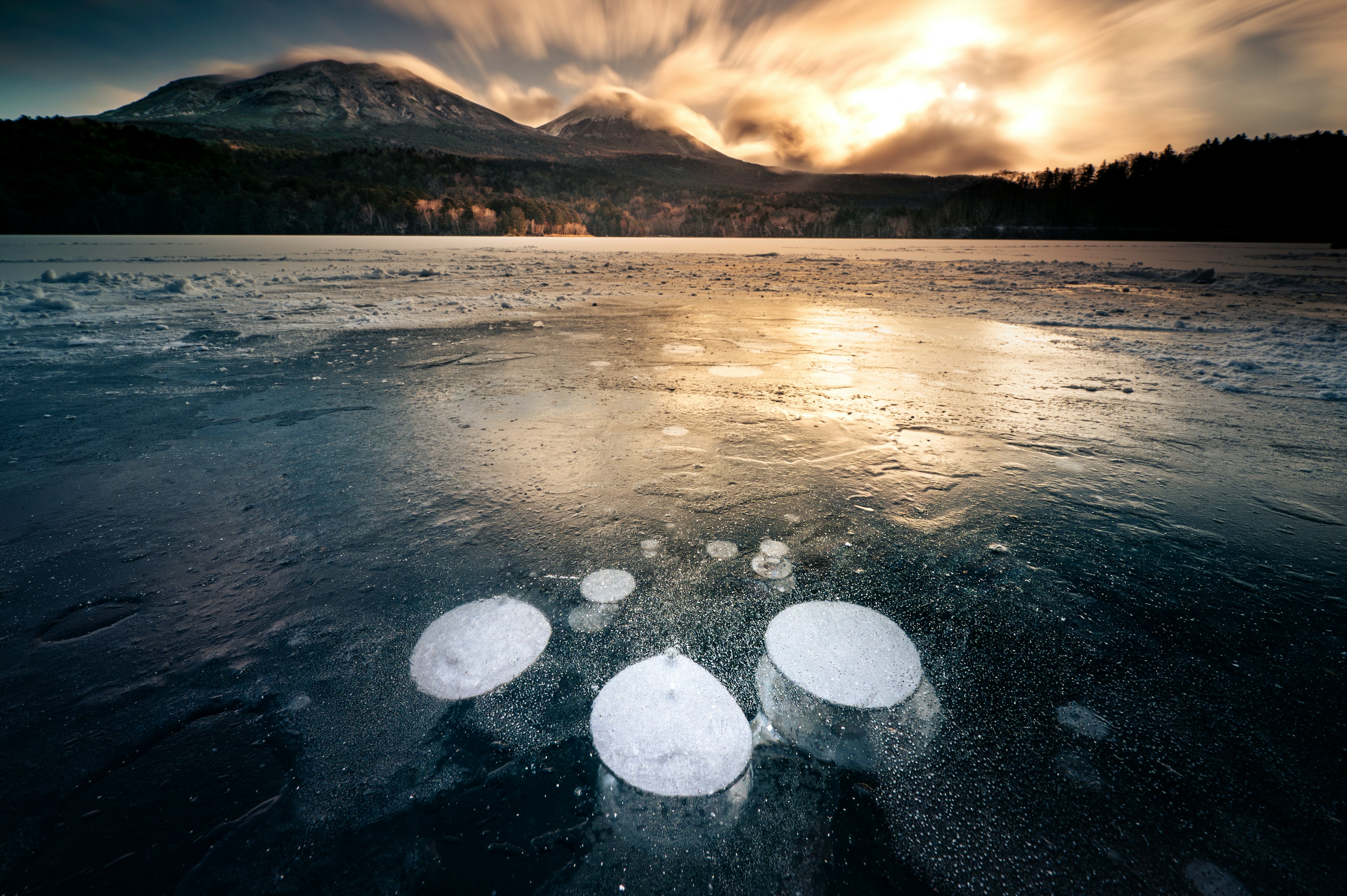 Bubbles trapped under ice with a stunning mountain backdrop