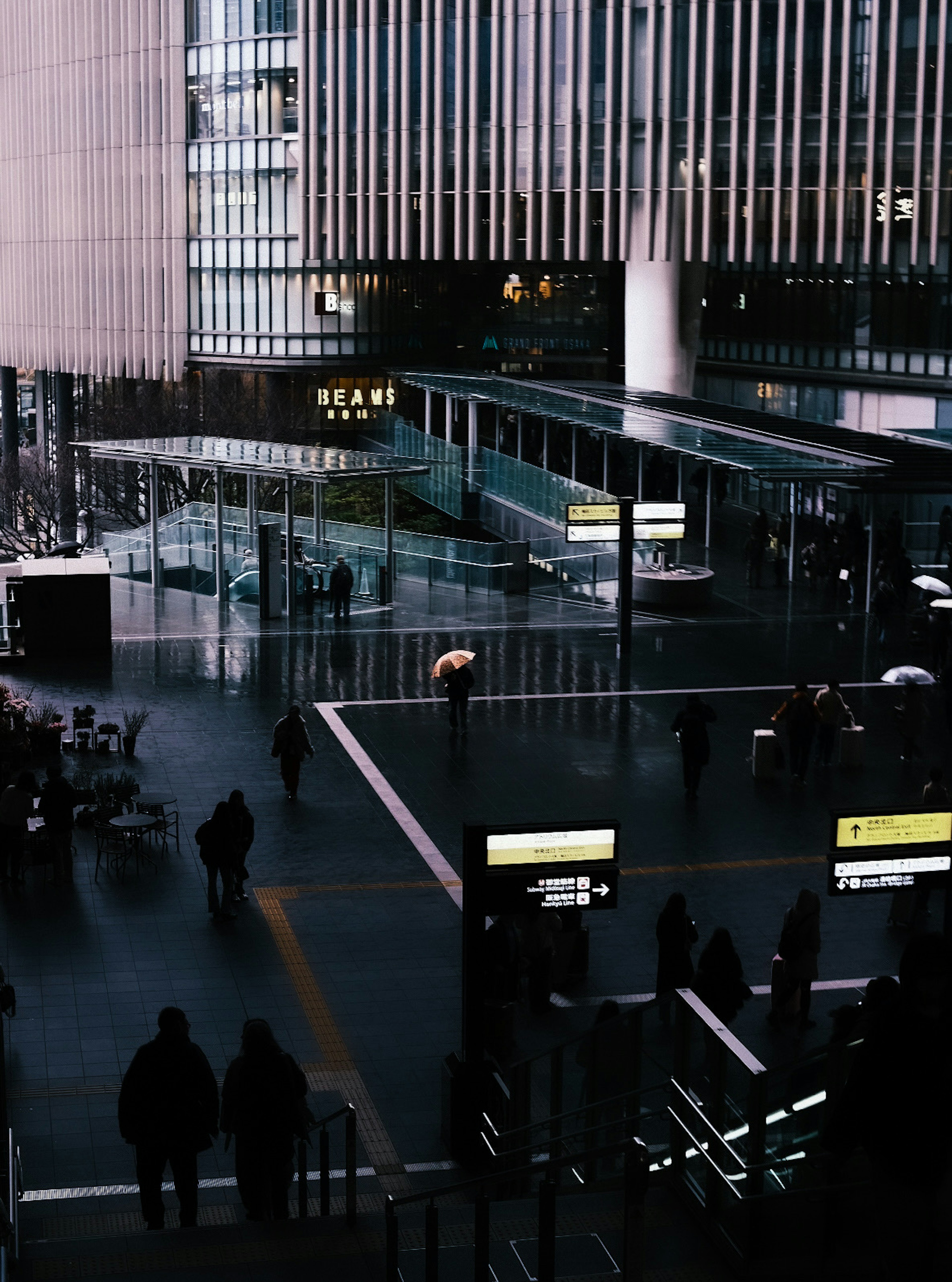 Interior de una estación de tren con personas caminando en un entorno urbano oscuro