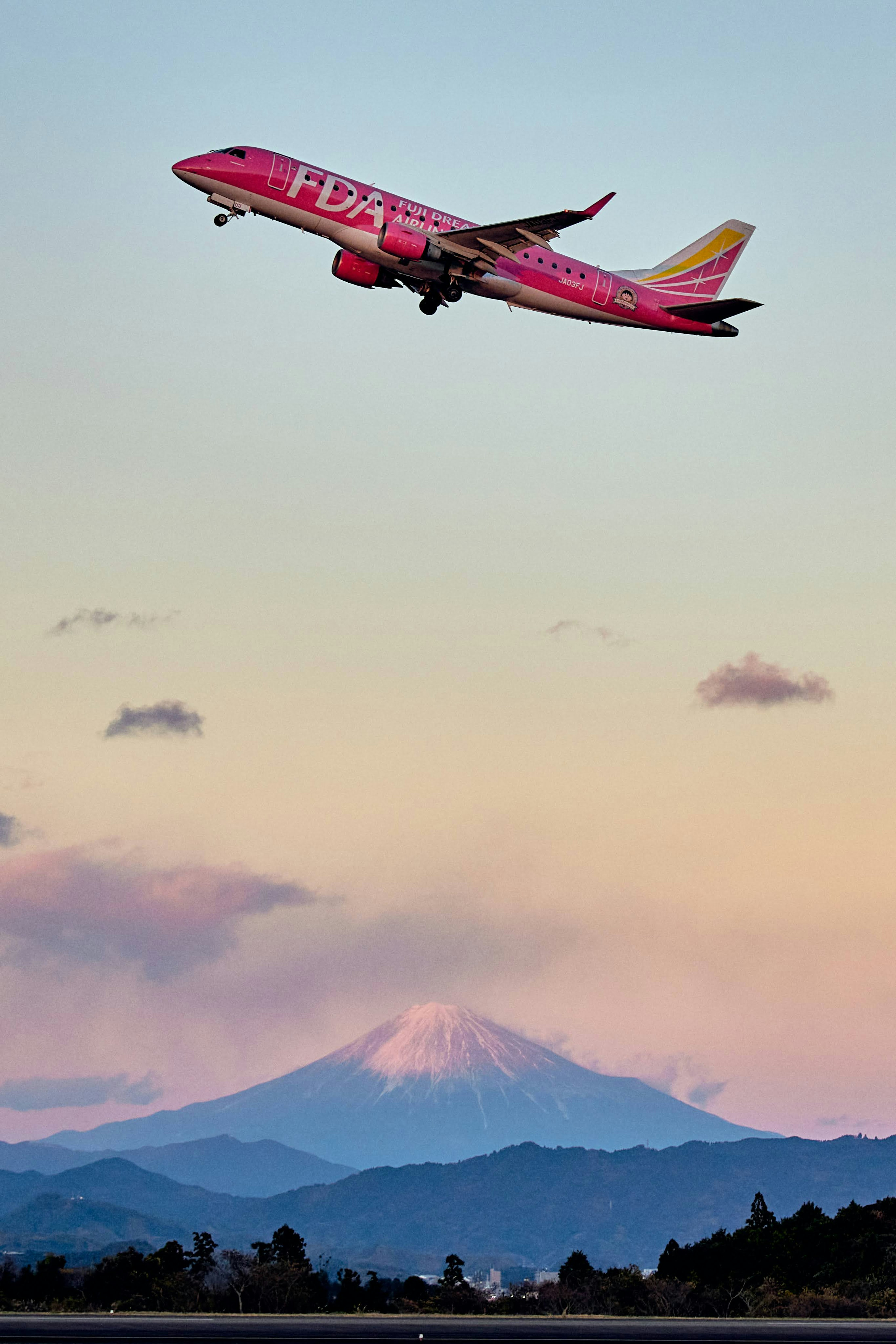 Avión rosa despegando con el monte Fuji al fondo