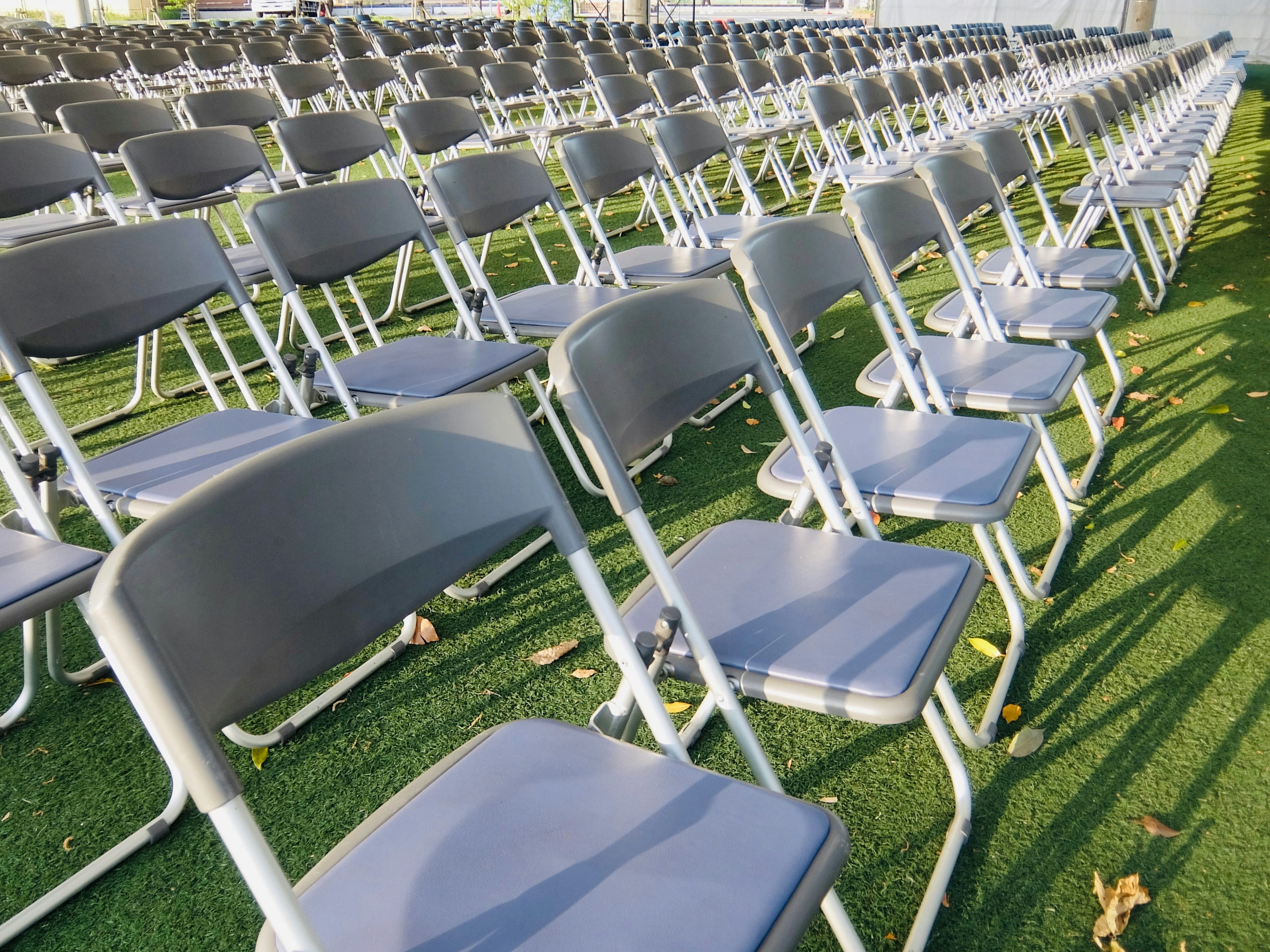 Rows of folding chairs arranged on green grass