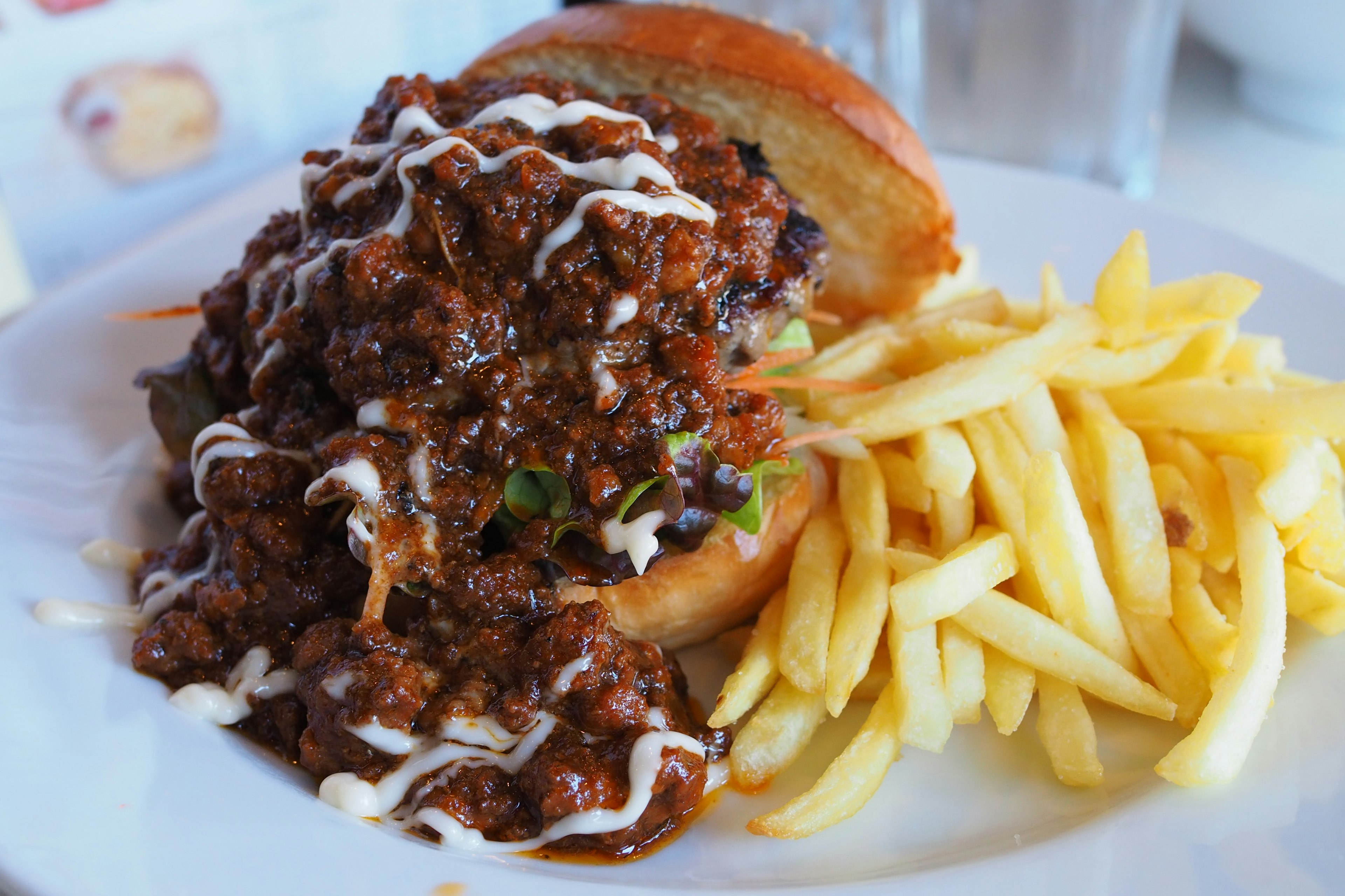 Burger melimpah dengan saus daging kaya disajikan dengan kentang goreng