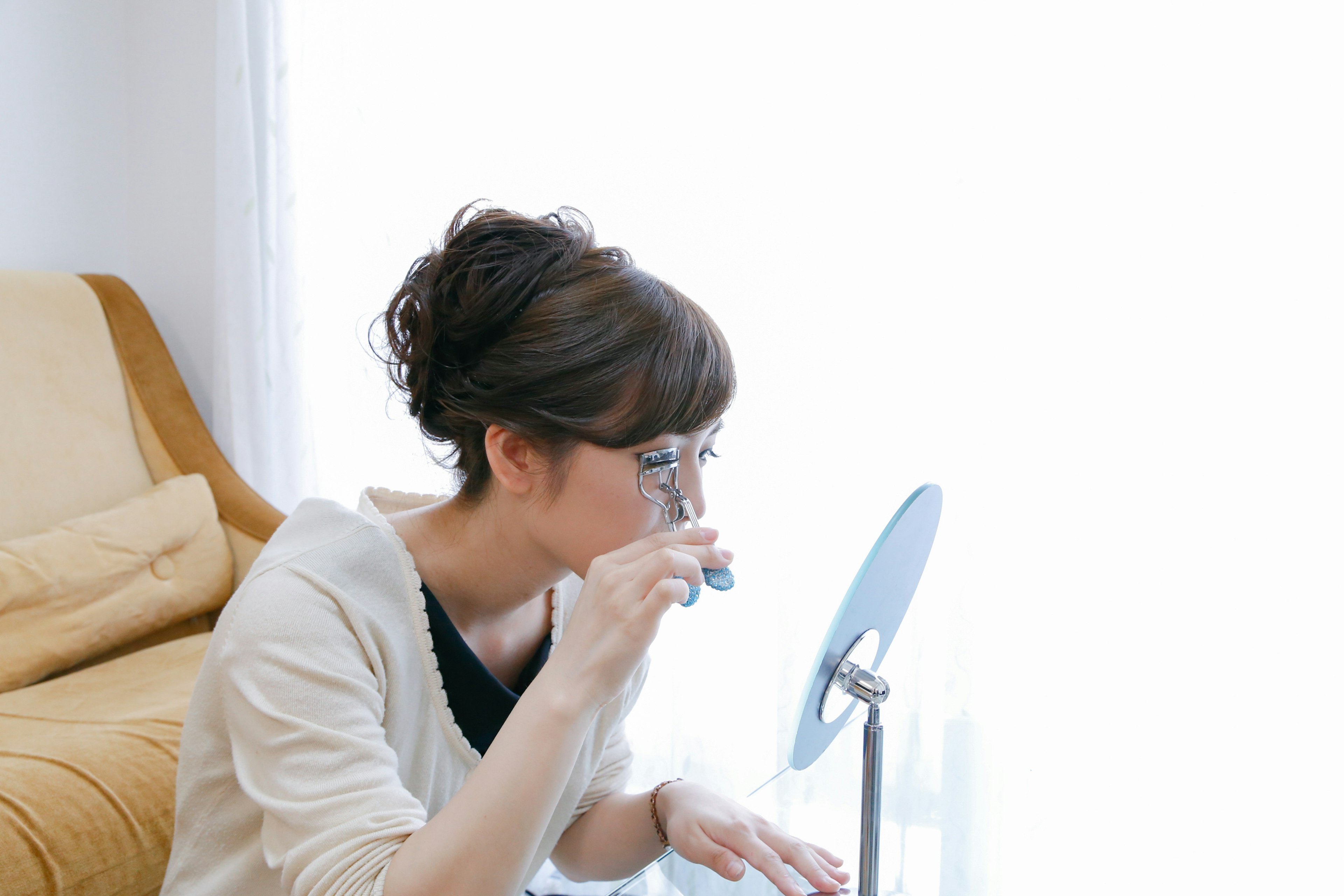 Woman examining something closely in front of a mirror in a bright indoor setting