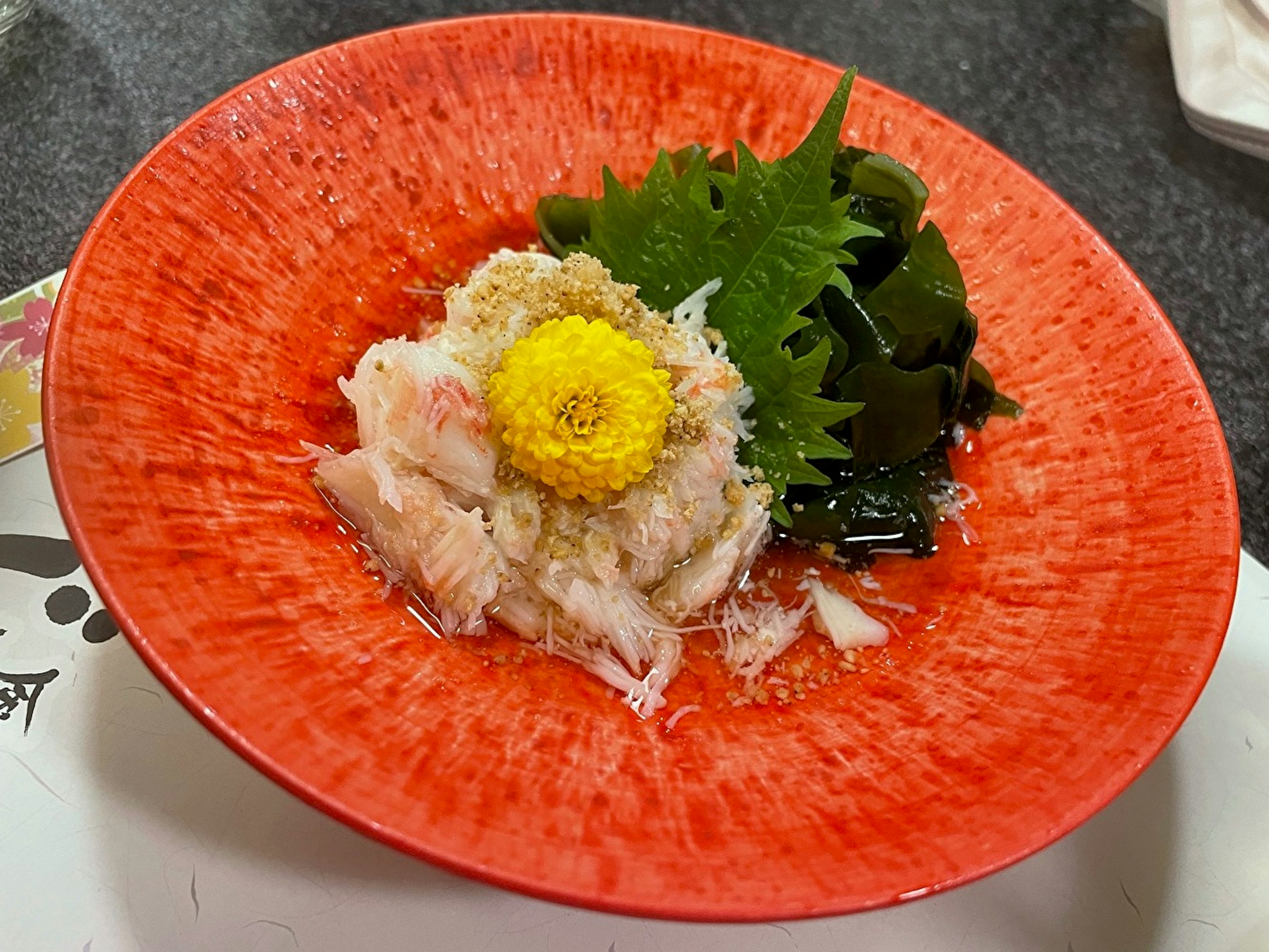 赤い皿に盛られた新鮮な魚の刺身と緑の葉野菜