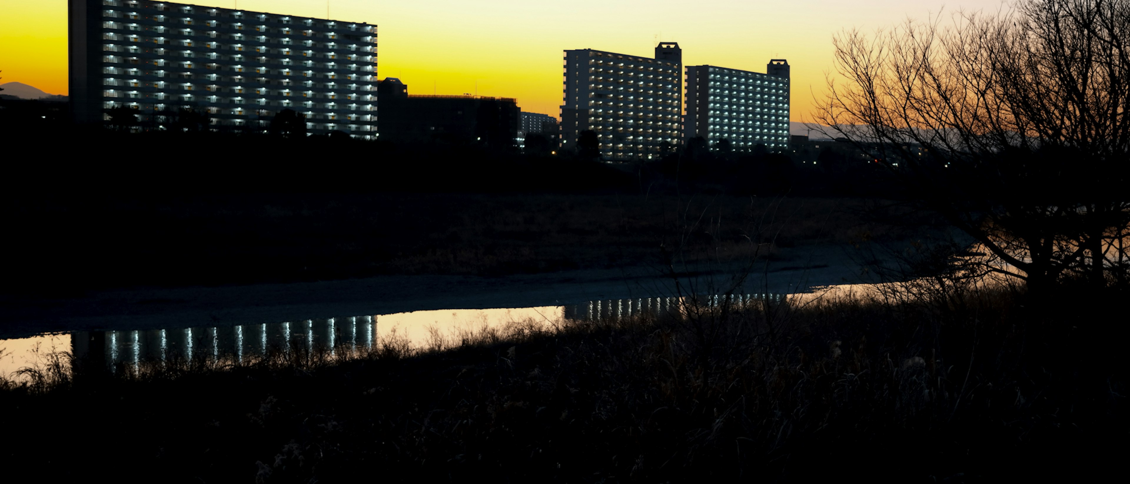 Hochhäuser silhouettiert gegen einen Sonnenuntergang mit Reflexionen im Fluss