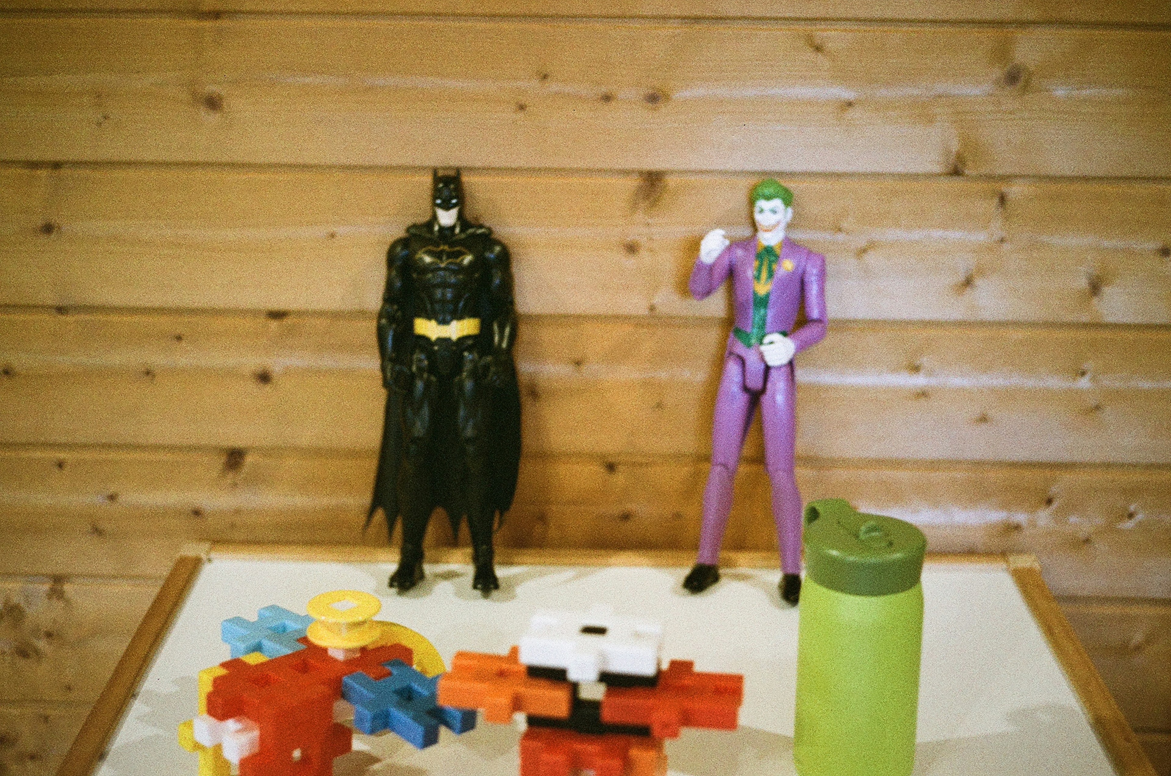 Figur Batman dan Joker di atas meja dengan blok warna-warni dan wadah hijau