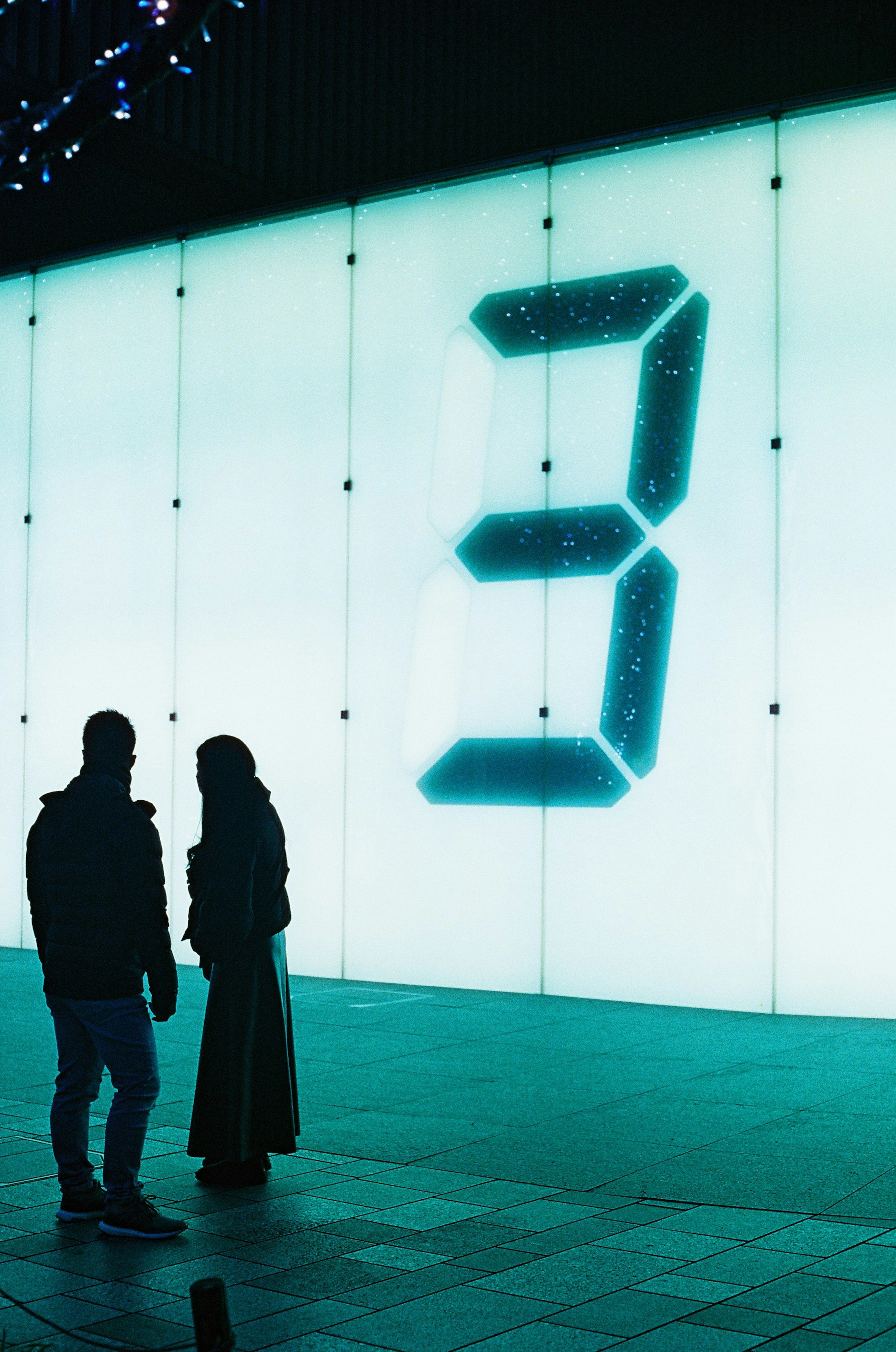 Silhouette of two people in front of a glowing number 3