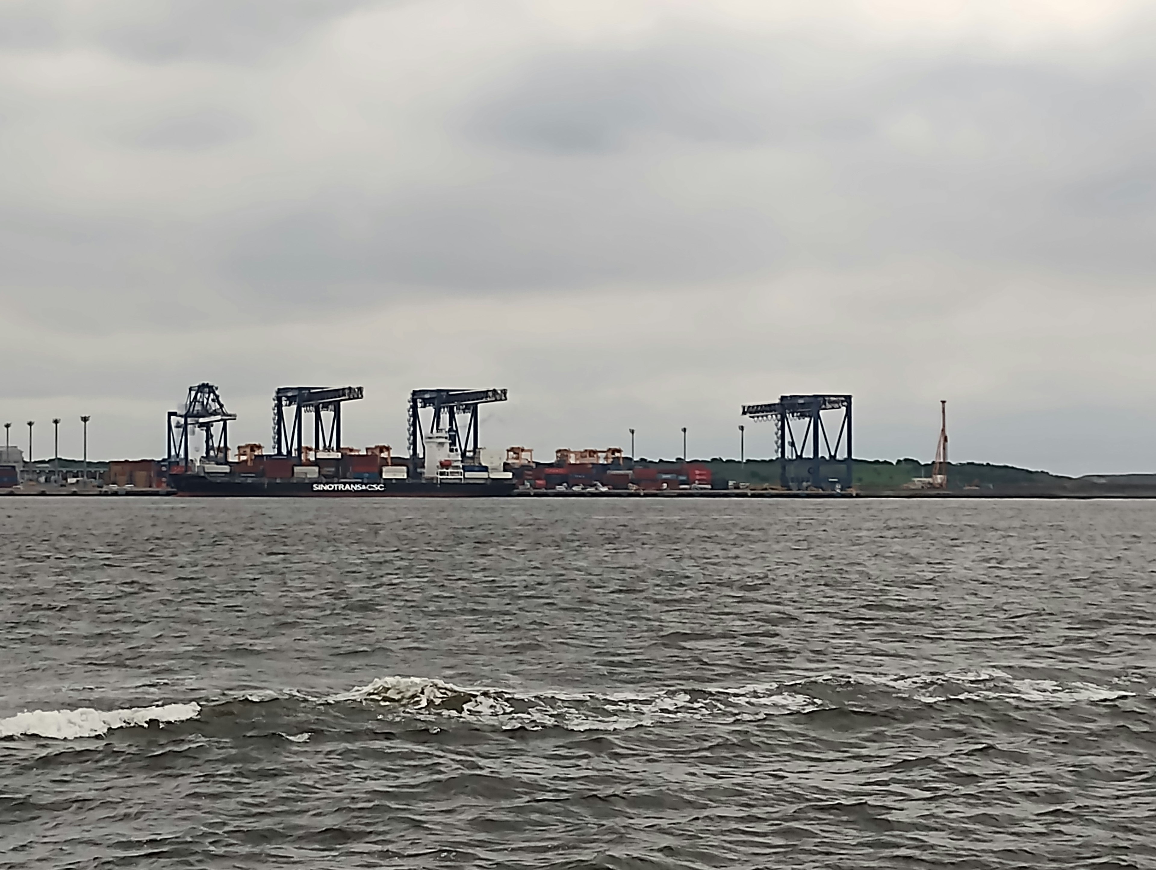 海上に浮かぶ貨物船とクレーンのある港の風景