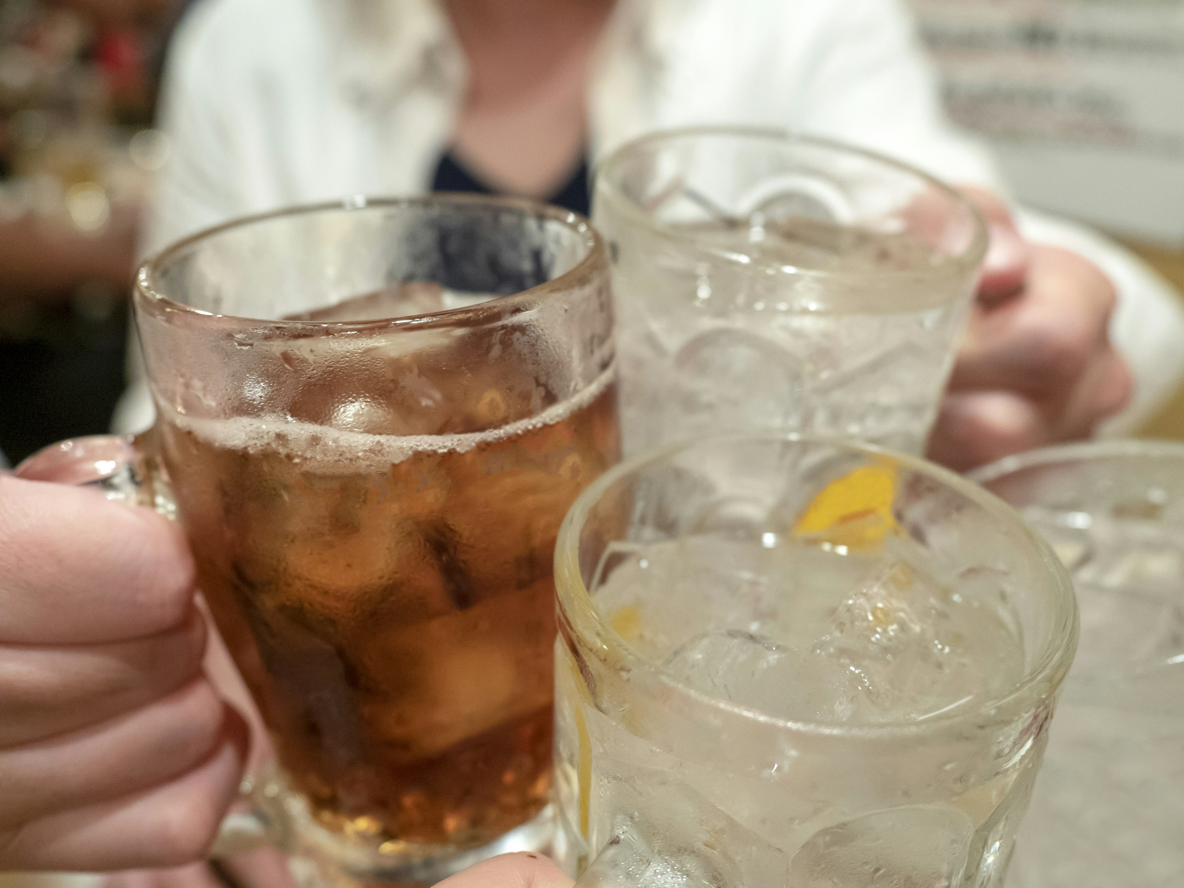 Close-up of glasses raised for a toast with dark and clear beverages