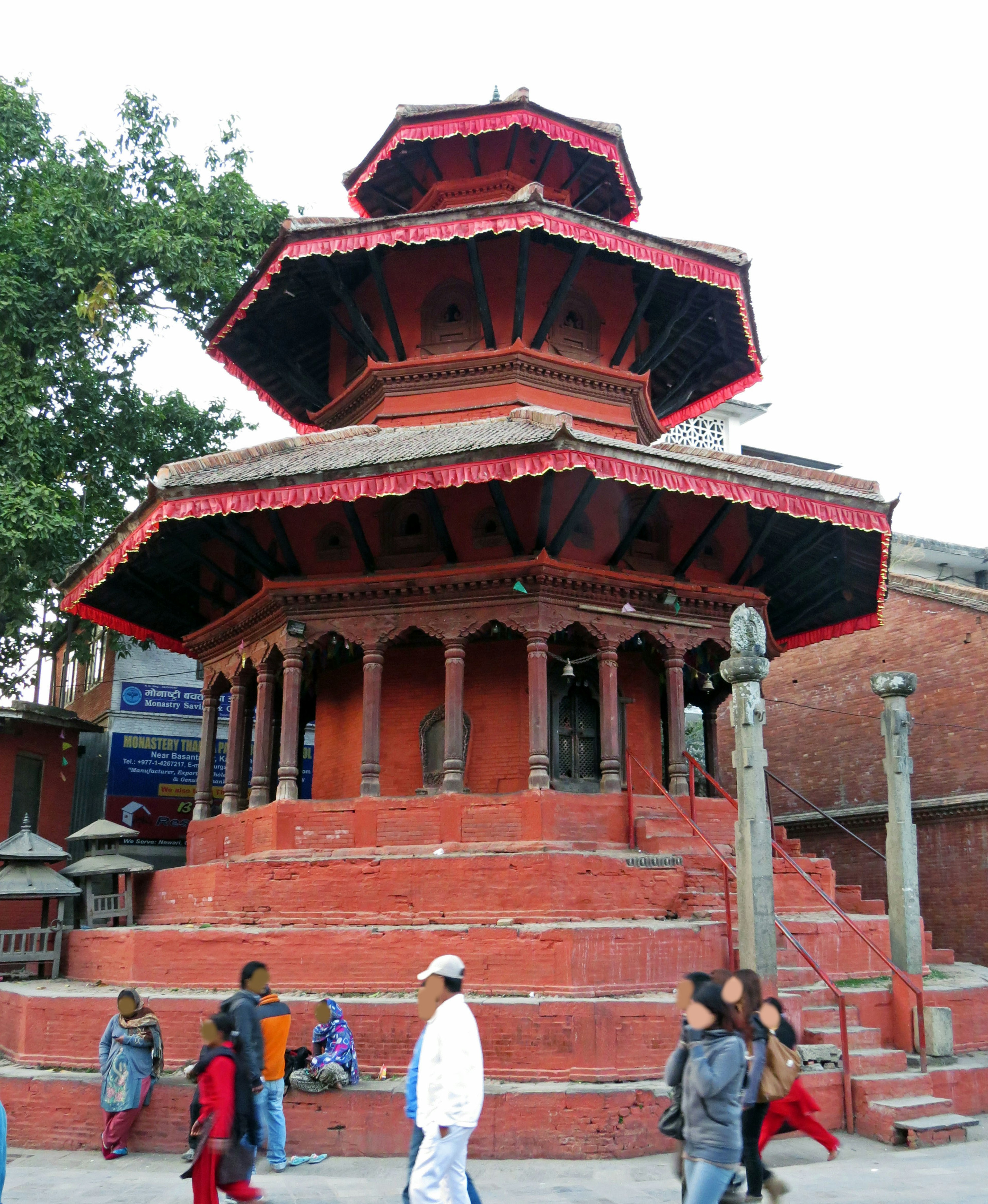 Multi-tiered temple with a red roof and surrounding pedestrians