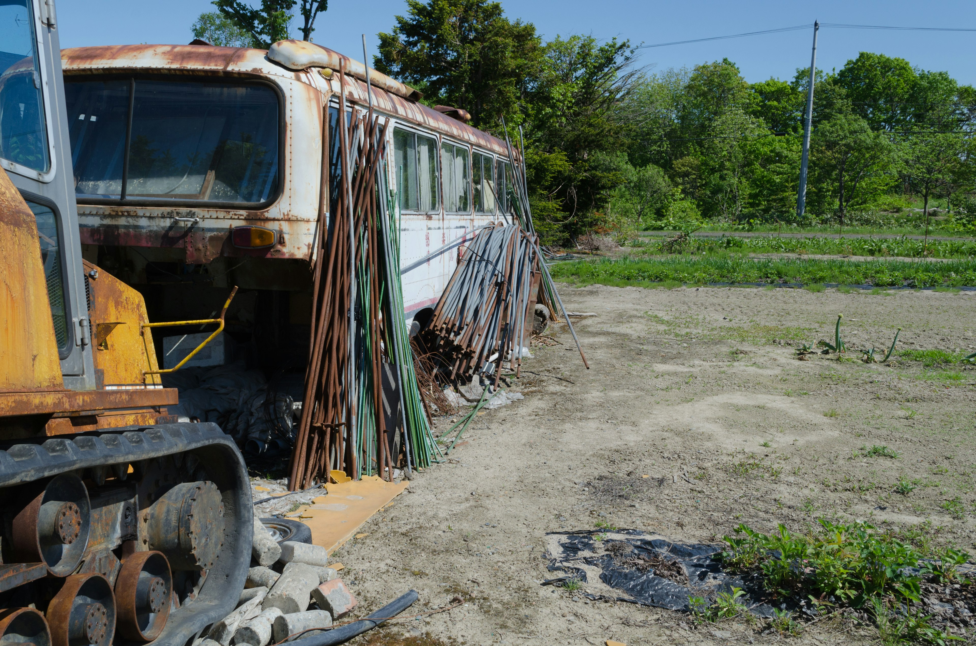 Autobus arrugginito con barre metalliche su un terreno desolato