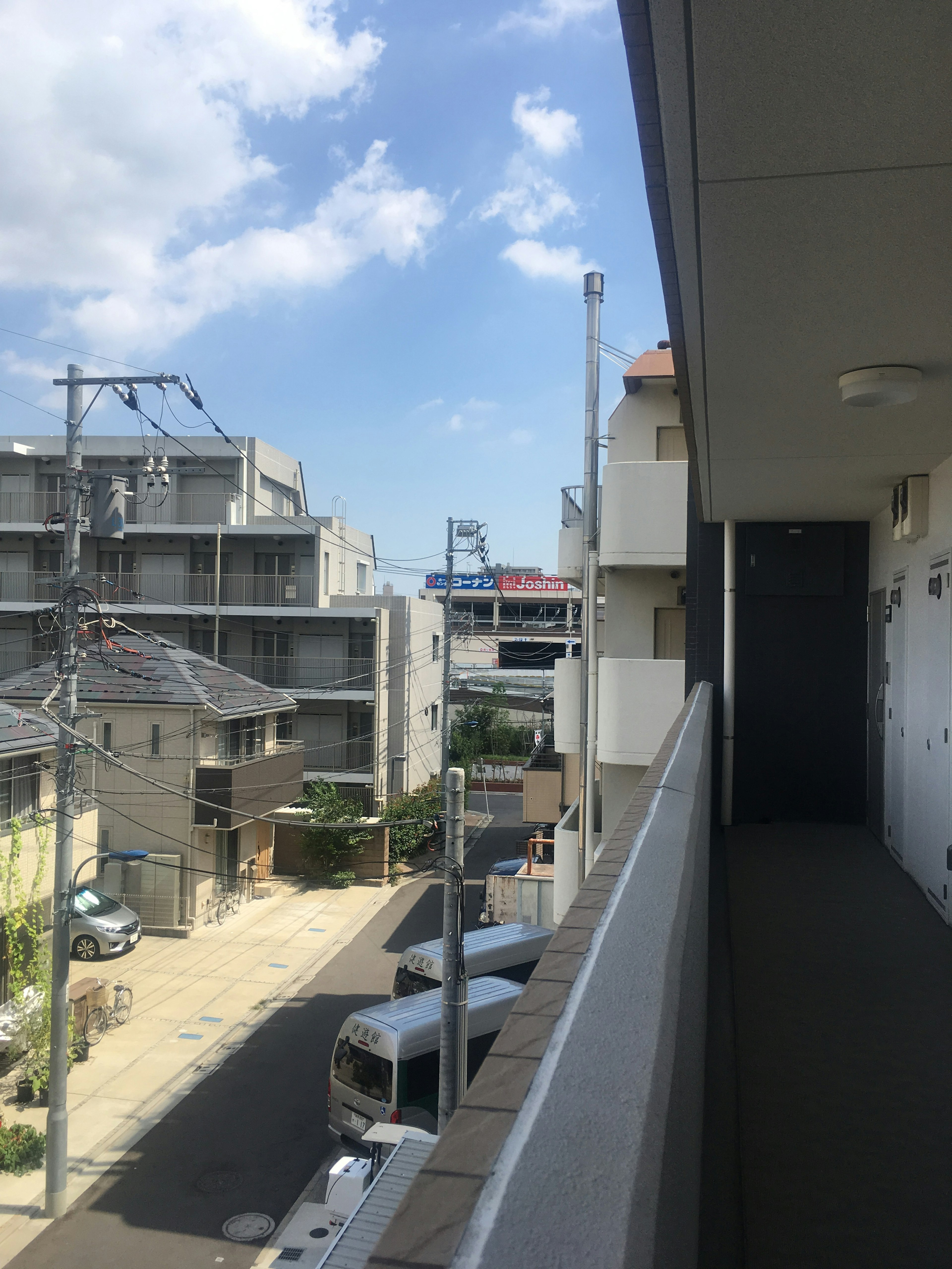 View from an apartment balcony showing nearby buildings and a clear sky