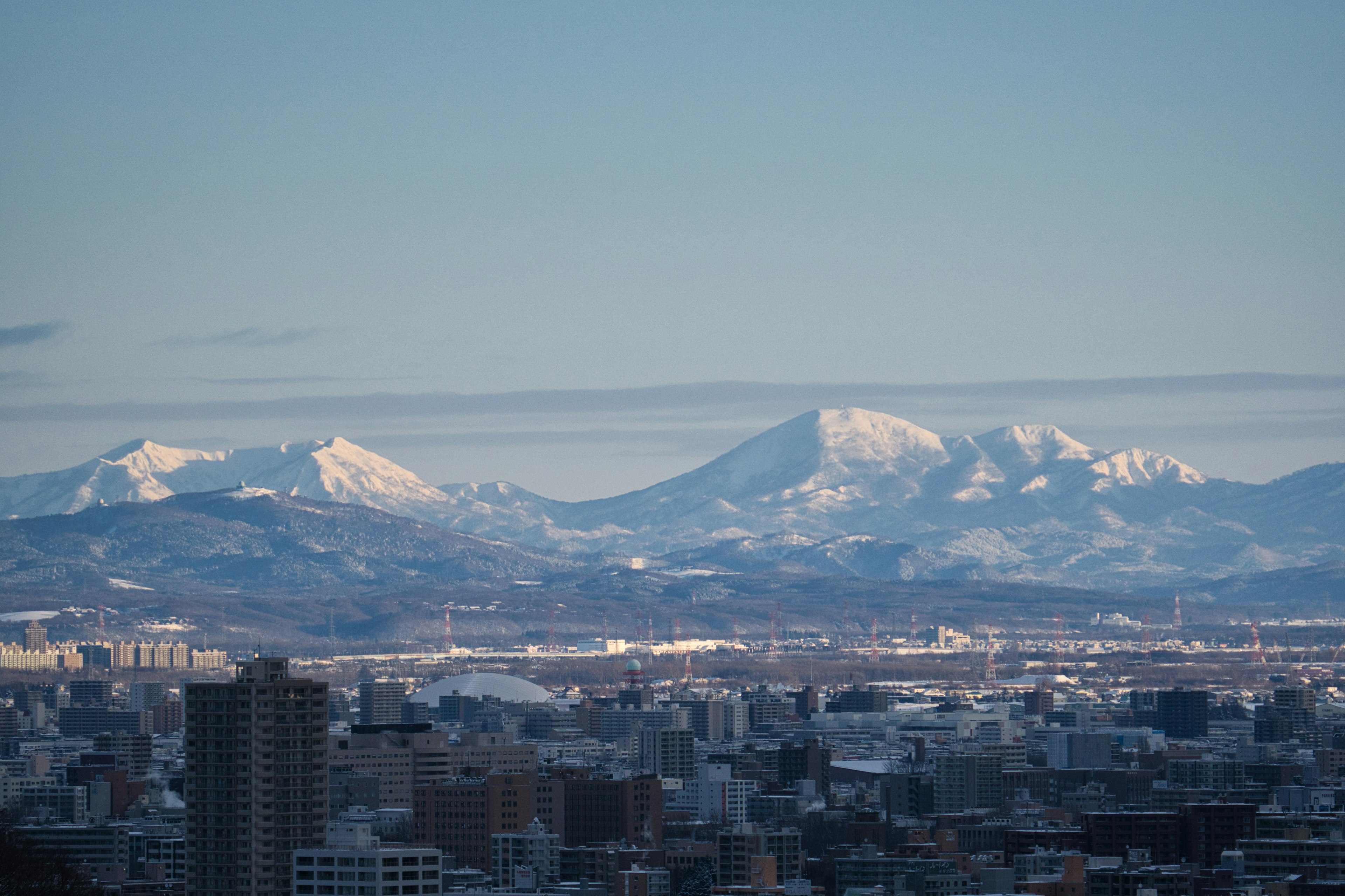 Snow-covered mountains with a cityscape in the foreground