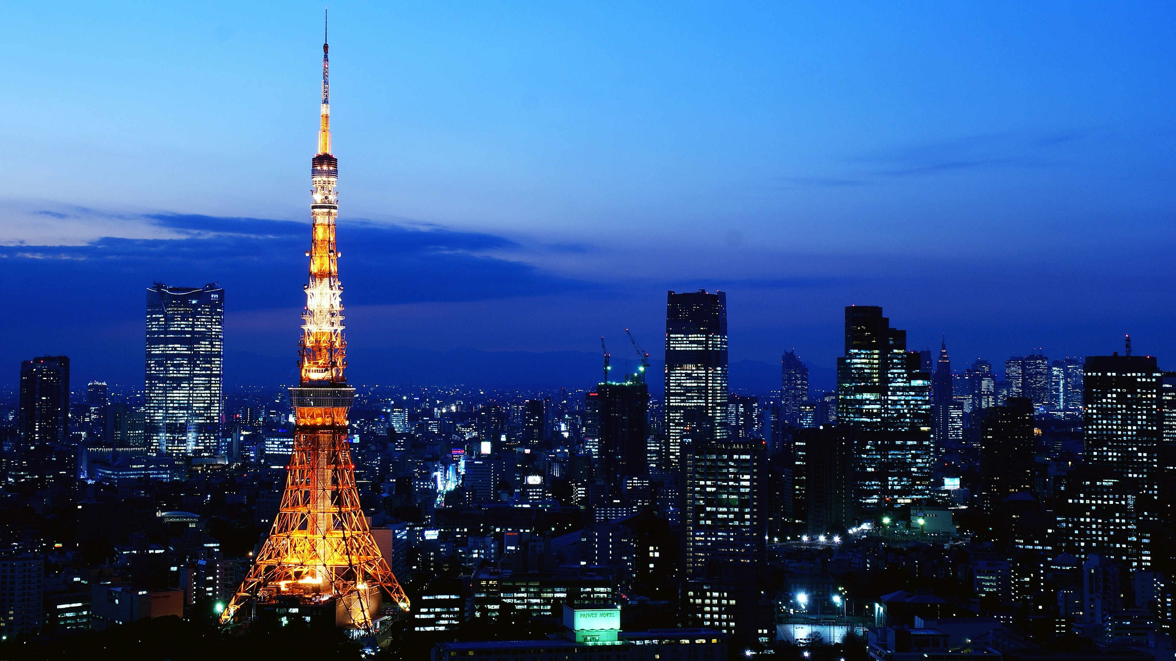 東京塔在夜間照亮，背景是城市天際線