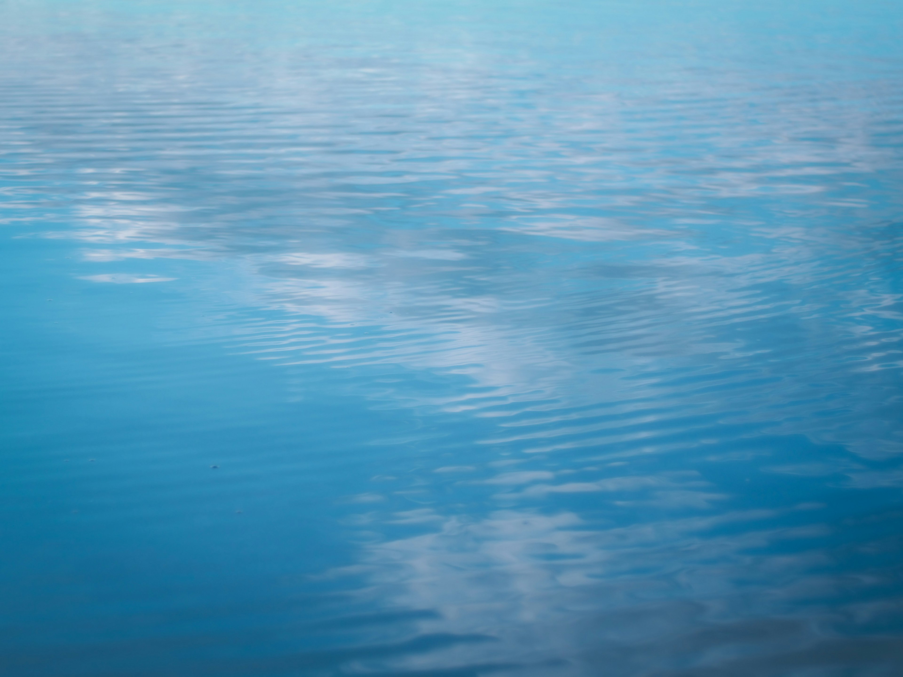 Ruhige blaue Wasseroberfläche, die Wolken spiegelt