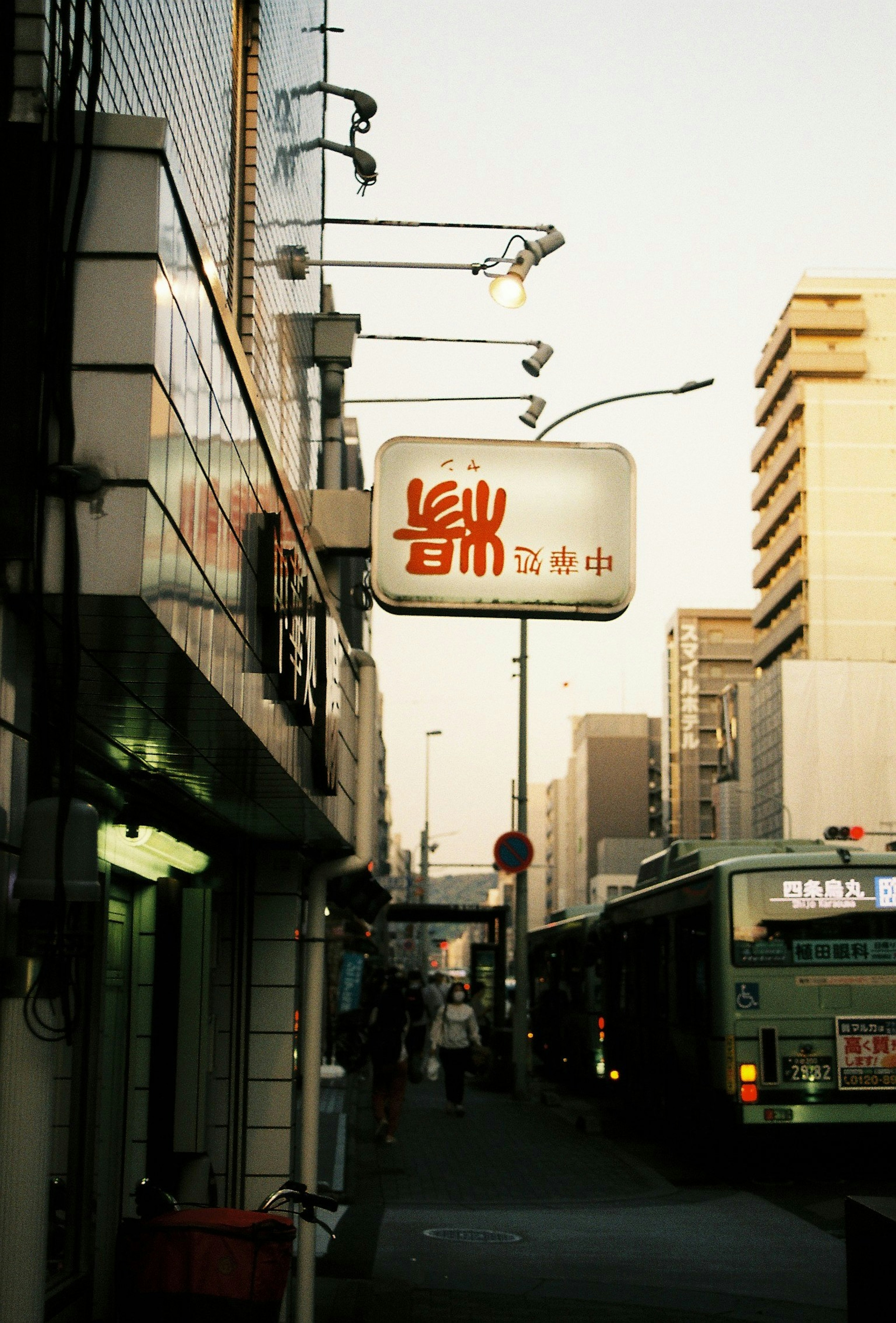 Street view at dusk featuring a prominent sign and a bus