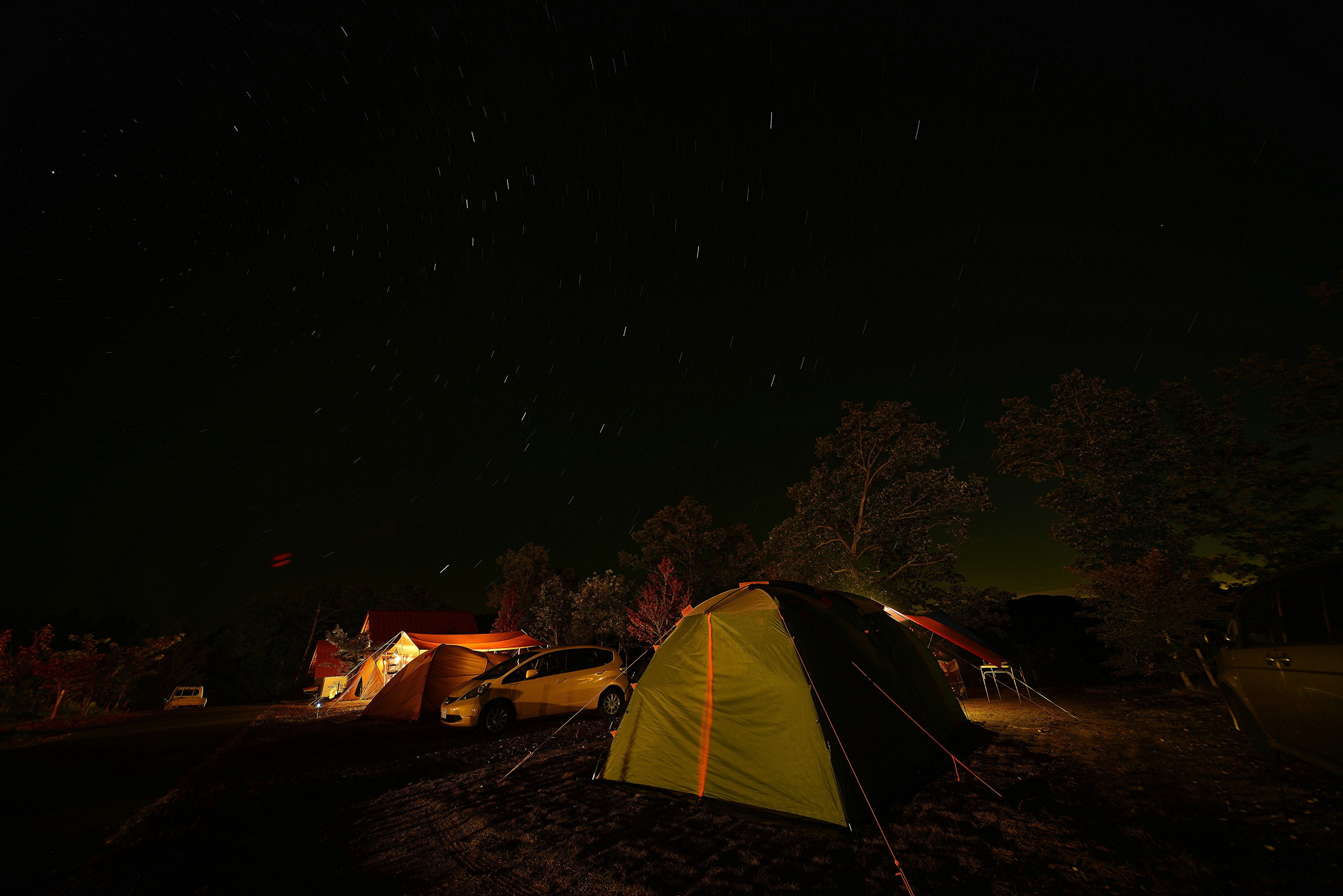 Campingplatz bei Nacht mit hellen Sternen Zelte angeordnet und Bäume im Hintergrund