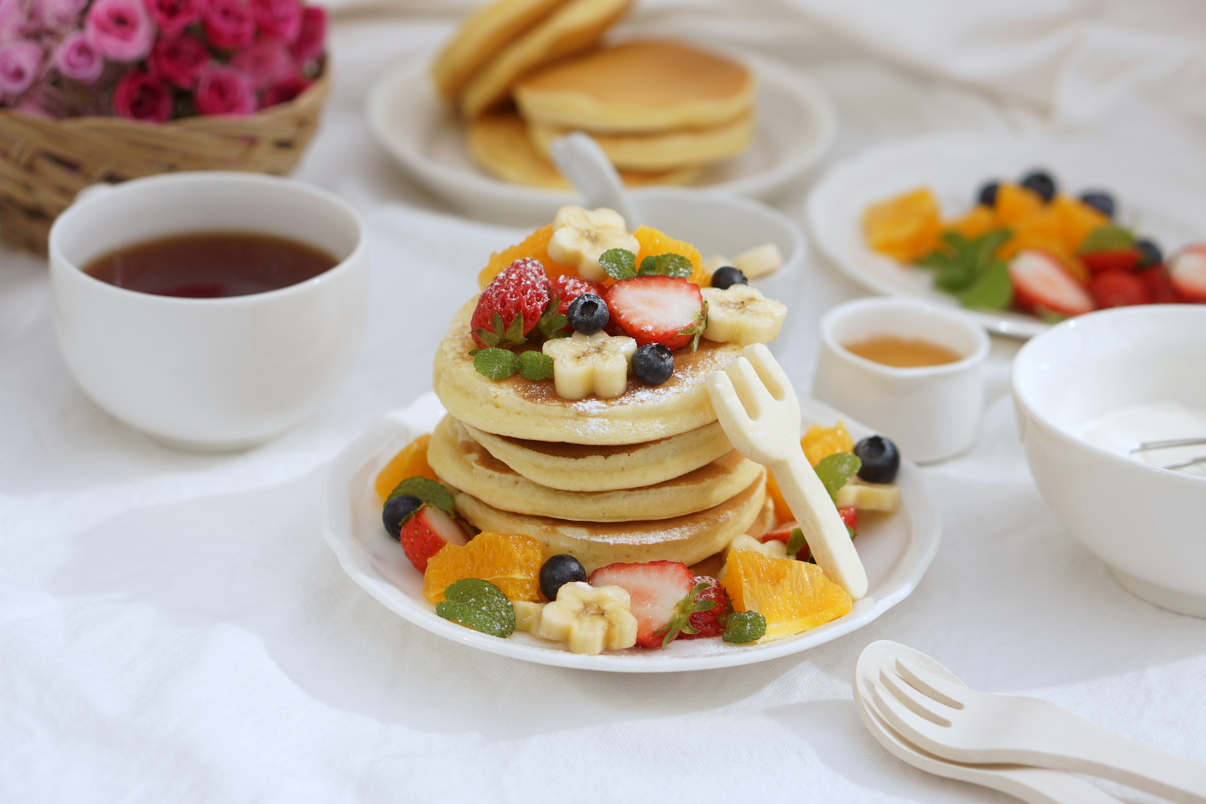 Petit déjeuner avec des pancakes garnis de fruits et du thé aux herbes