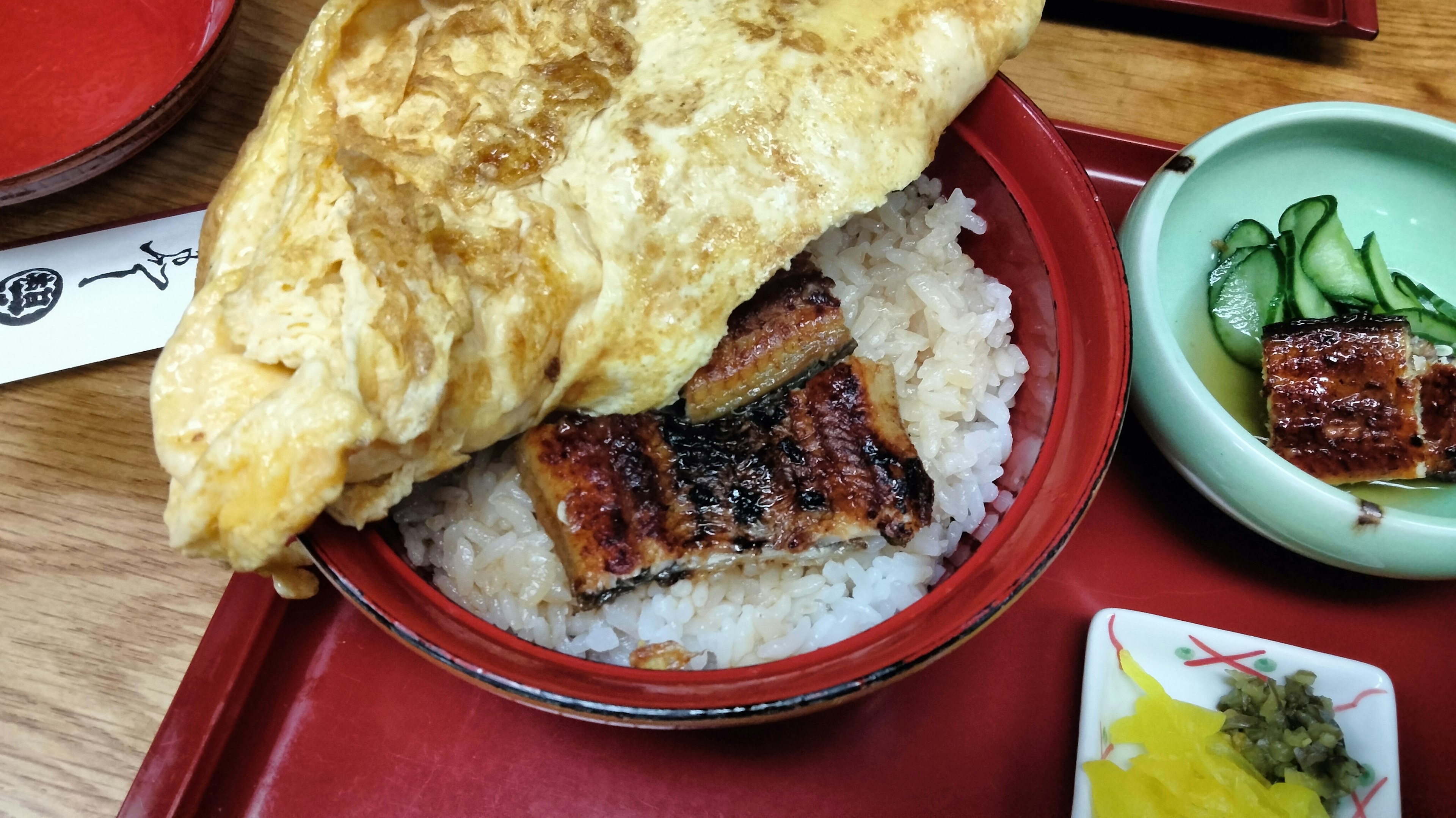 ご飯の上に焼きうなぎとふわふわの卵焼きがのった丼の写真