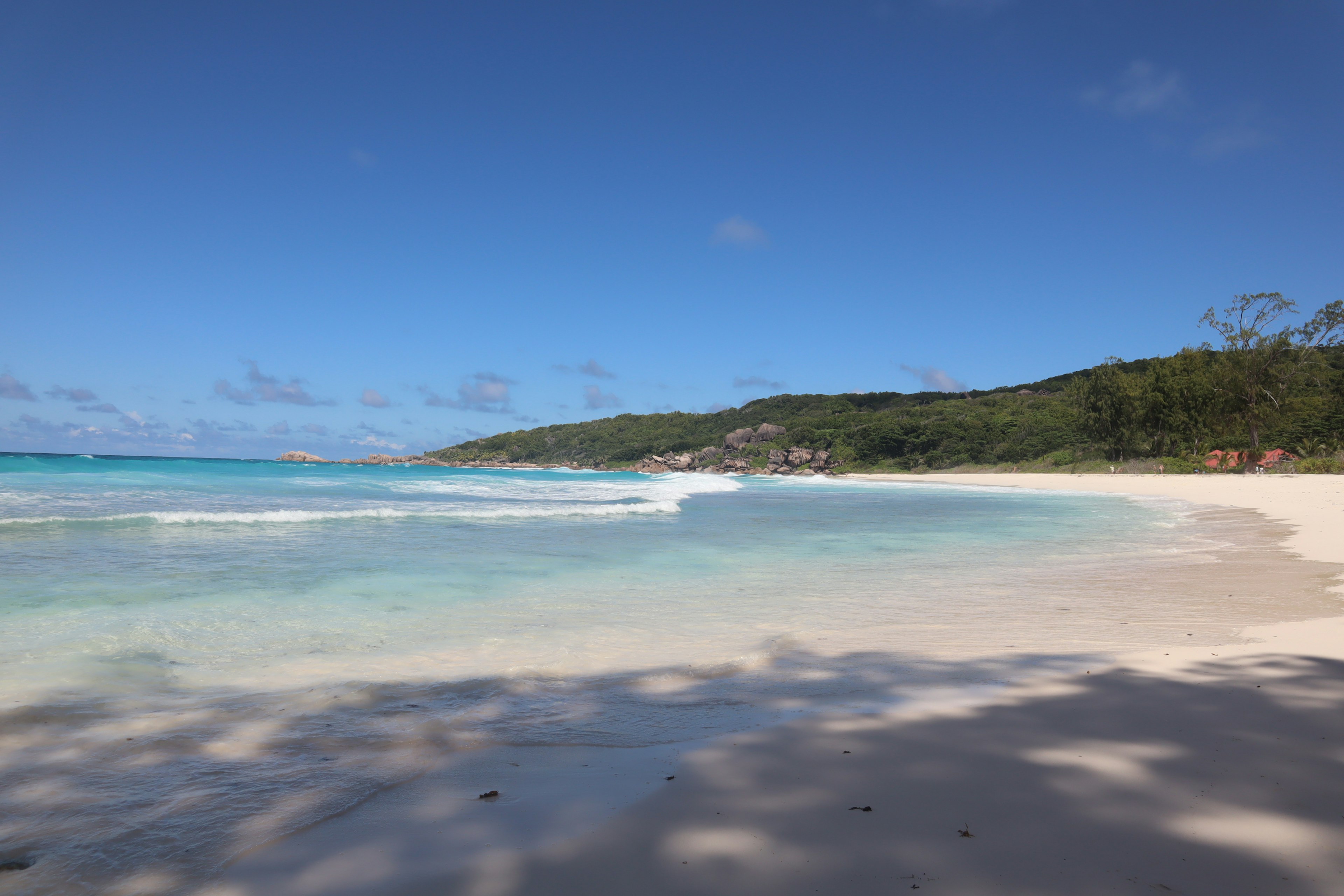 Vista di spiaggia panoramica con acqua blu chiaro e sabbia bianca