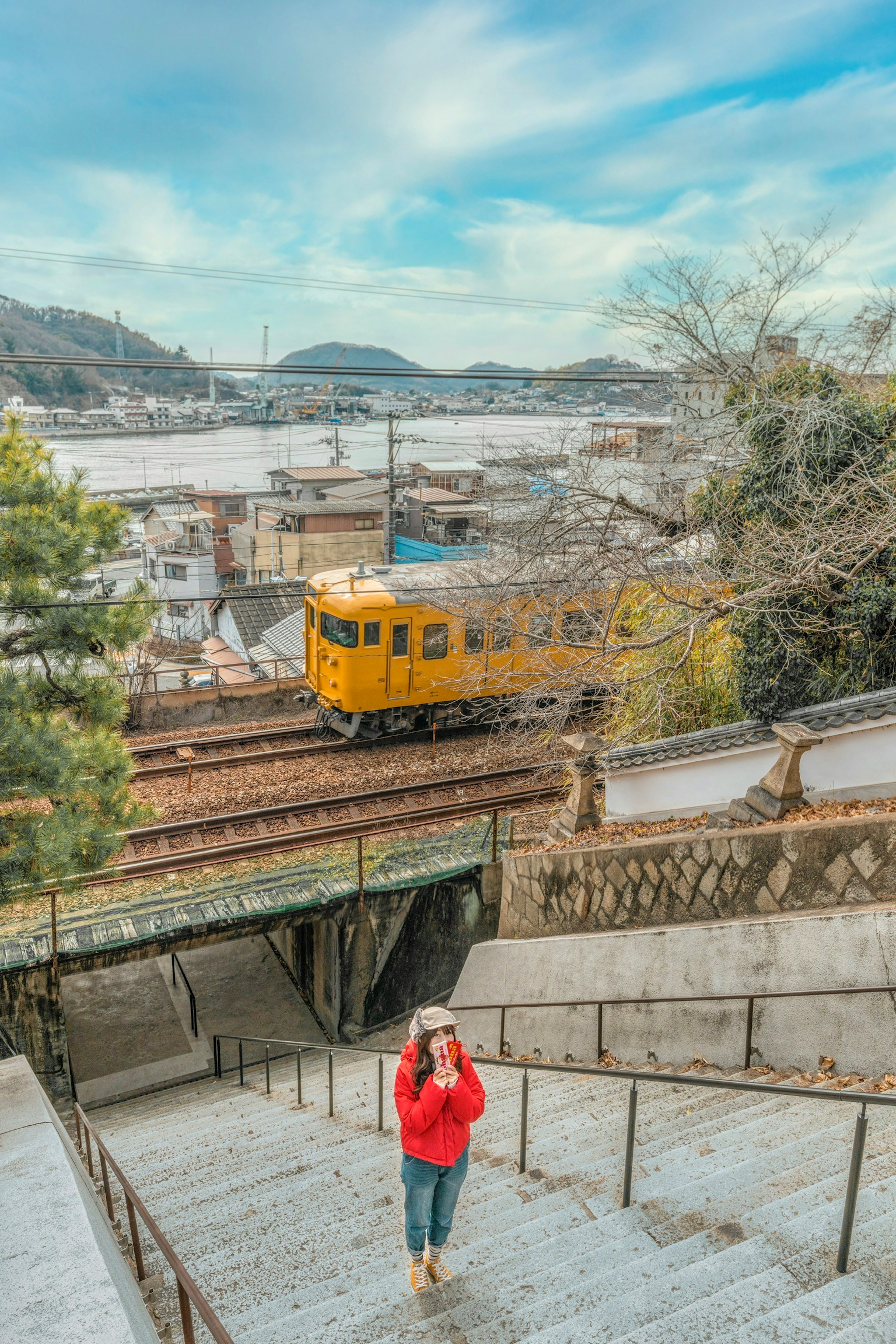 一名女性在樓梯上走下，背景有一列黃色火車