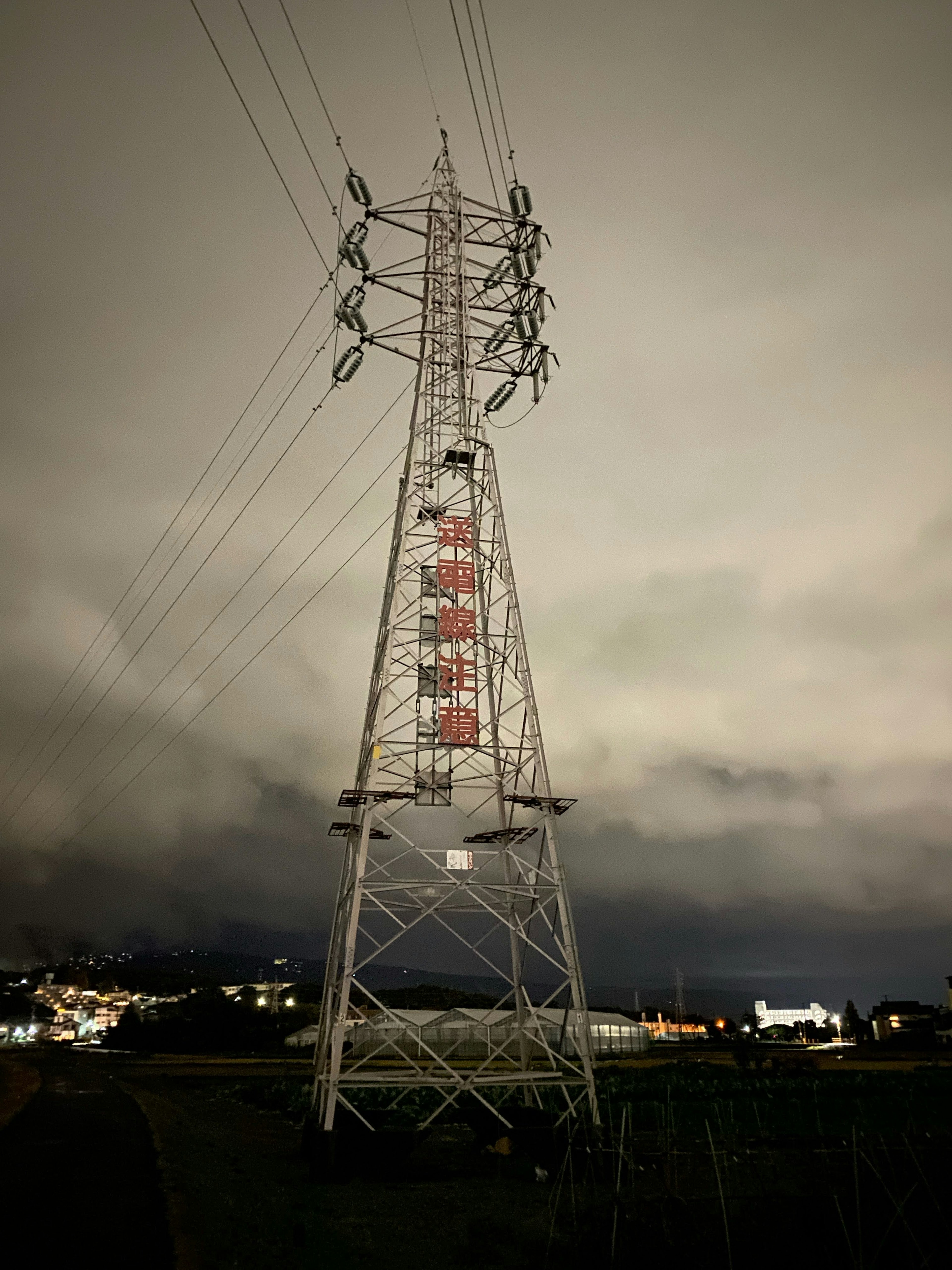 High voltage power tower against a night sky with surrounding landscape